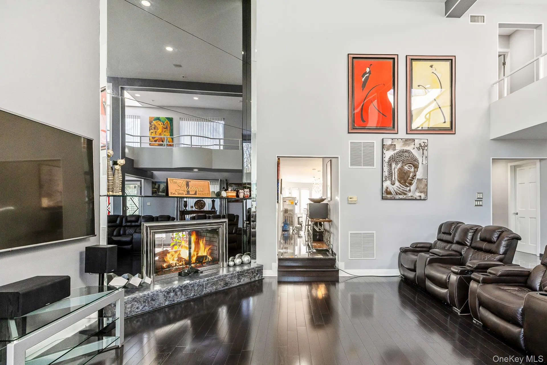 Living room with a towering ceiling, dark wood-type flooring, and a fireplace Living room with a towering ceiling, dark wood-type flooring, and a fireplace
