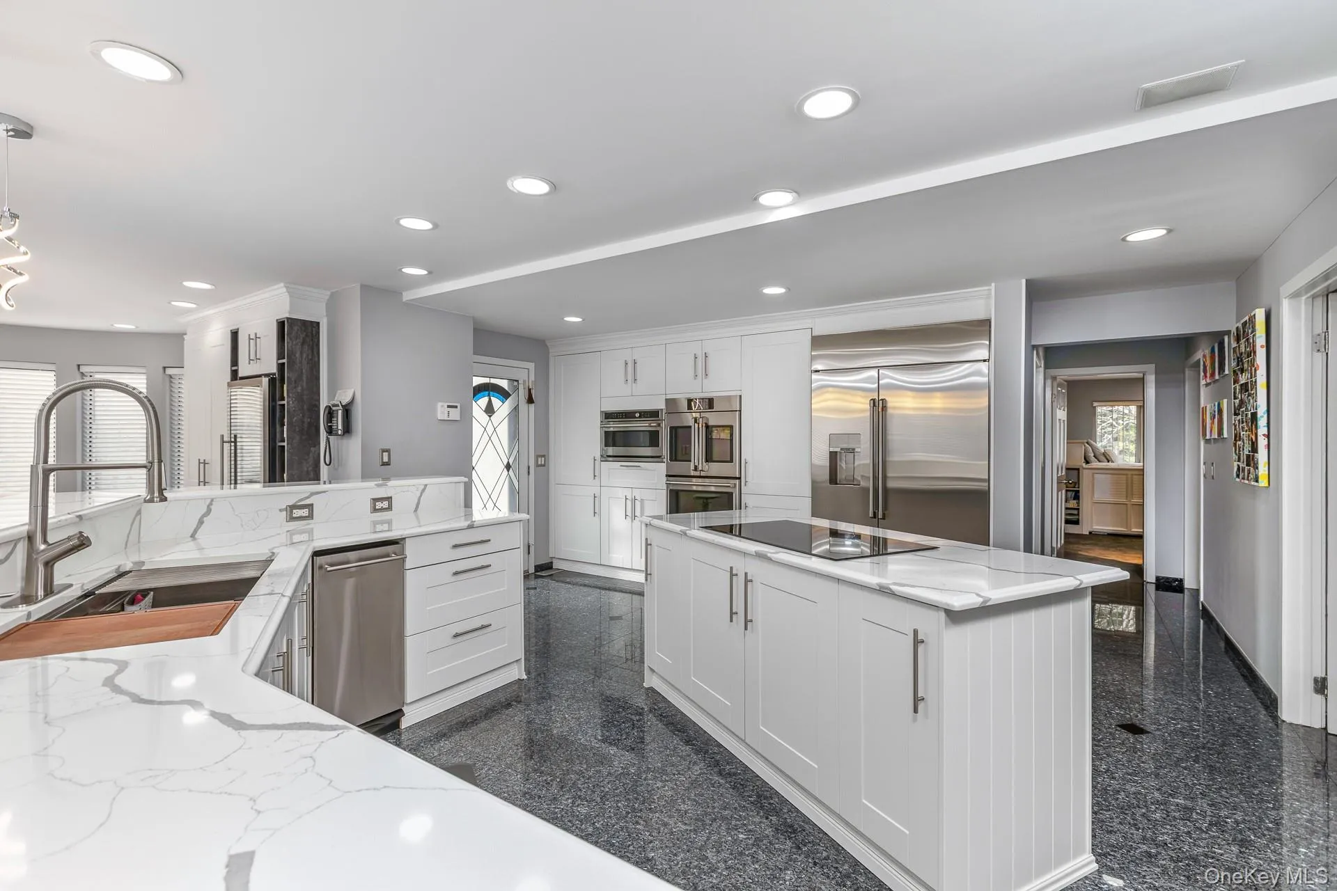 Kitchen with white cabinets, light stone counters, recessed lighting, granite tiled floors, and appliances with stainless steel finishes Kitchen with white cabinets, light stone counters, recessed lighting, granite tiled floors, and appliances with stainless steel finishes