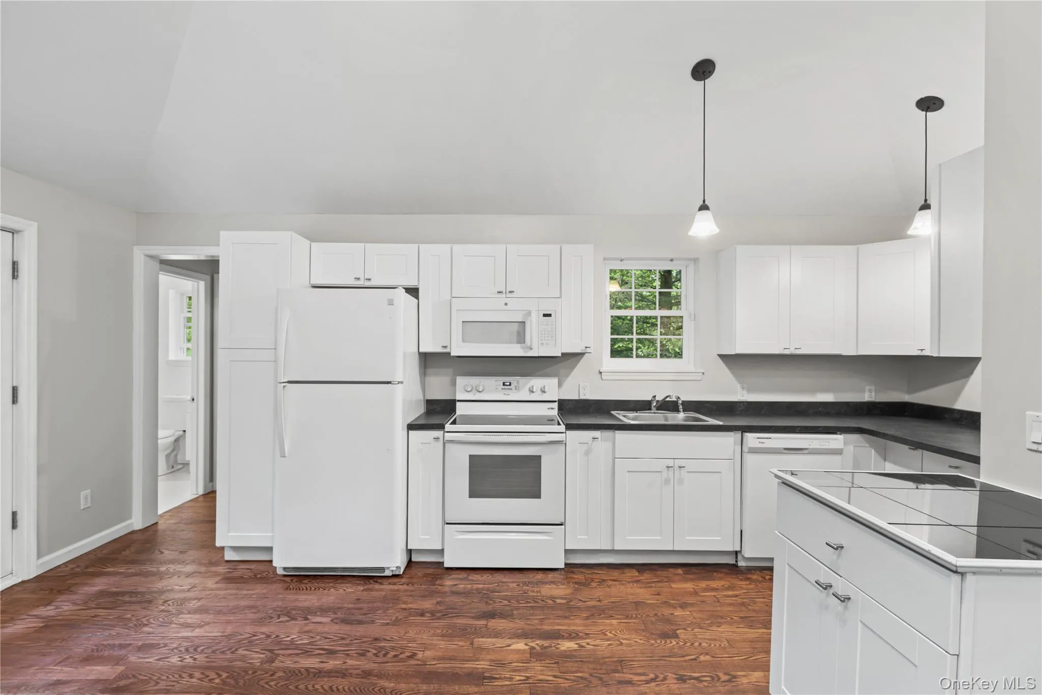 Kitchen with white appliances, sink, vaulted ceiling, hanging light fixtures, and plenty of cabinets. Kitchen with white appliances, sink, vaulted ceiling, hanging light fixtures, and plenty of cabinets.