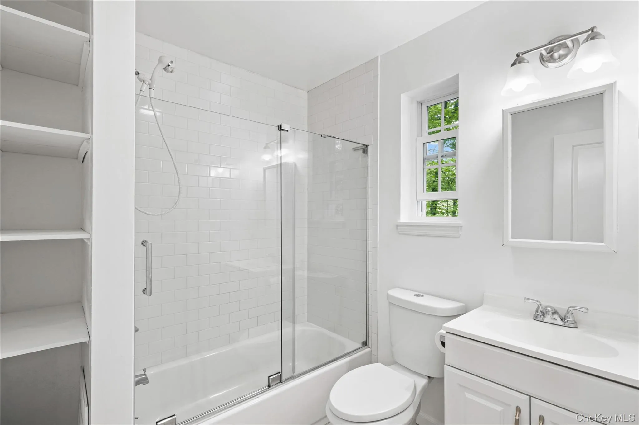 Bathroom with bath / shower combo with glass door, vanity, toilet plus storage. Bathroom with bath / shower combo with glass door, vanity, toilet plus storage.