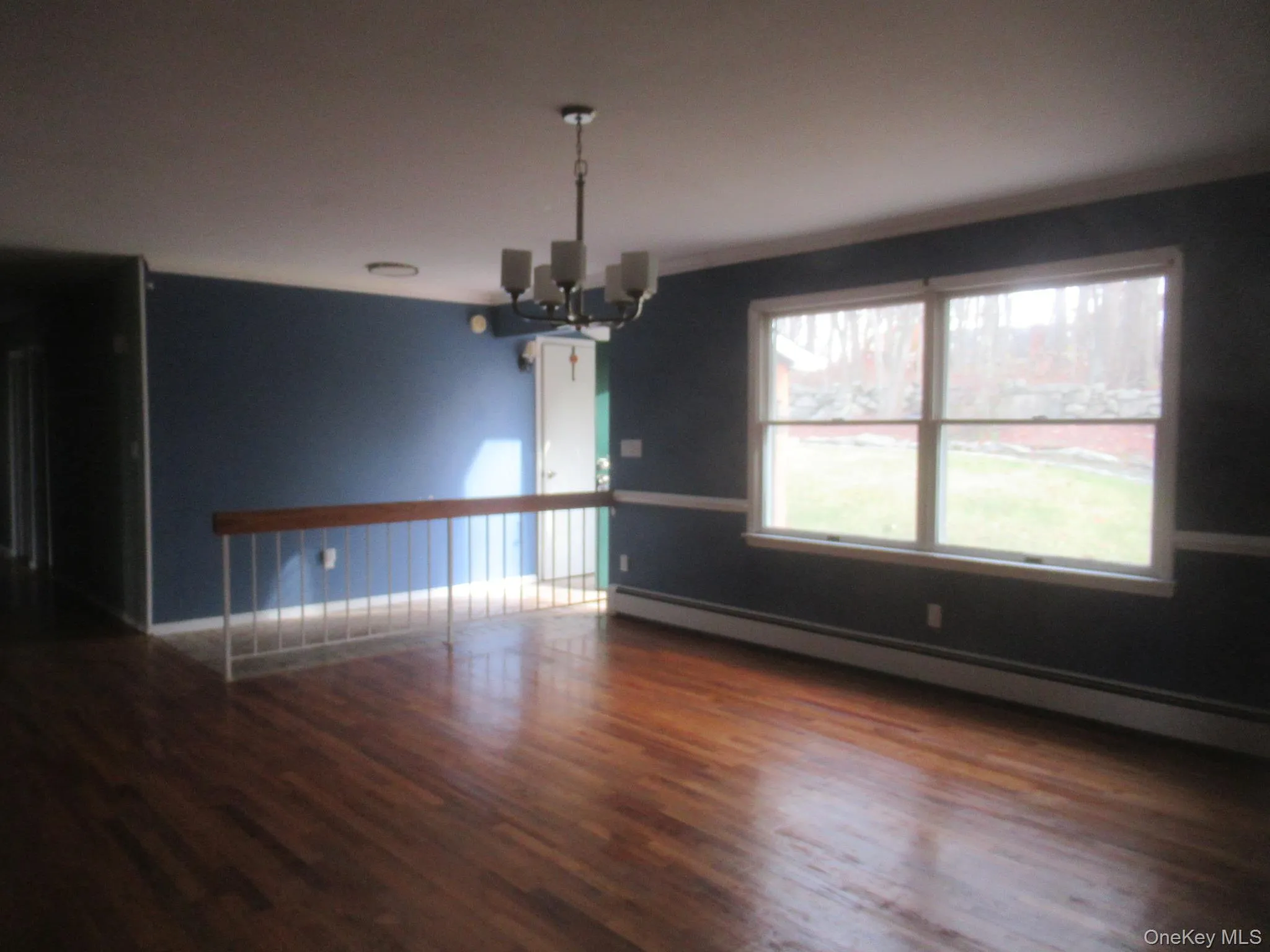 Unfurnished dining area with baseboard heating, a chandelier, and dark wood-style floors Unfurnished dining area with baseboard heating, a chandelier, and dark wood-style floors