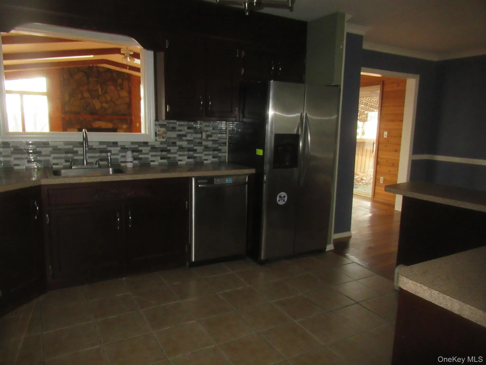 Kitchen with appliances with stainless steel finishes, tasteful backsplash, light countertops, light tile patterned floors, and vaulted ceiling Kitchen with appliances with stainless steel finishes, tasteful backsplash, light countertops, light tile patterned floors, and vaulted ceiling