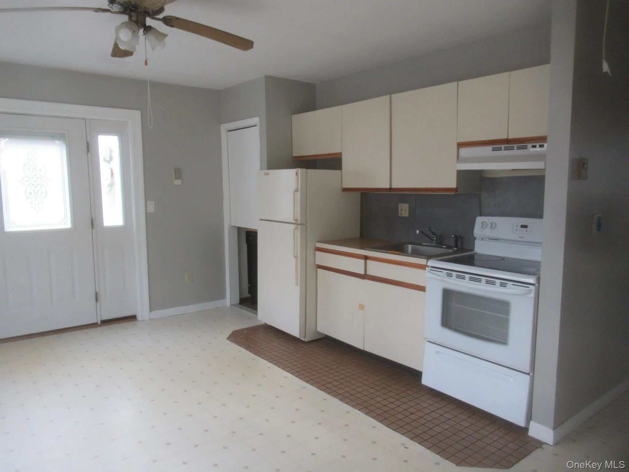Kitchen with white appliances, light flooring, under cabinet range hood, tasteful backsplash, and light countertops Kitchen with white appliances, light flooring, under cabinet range hood, tasteful backsplash, and light countertops