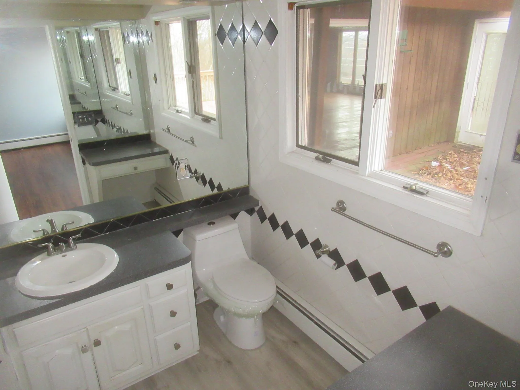 Half bathroom with light wood-style floors, vanity, a baseboard heating unit, and healthy amount of natural light Half bathroom with light wood-style floors, vanity, a baseboard heating unit, and healthy amount of natural light
