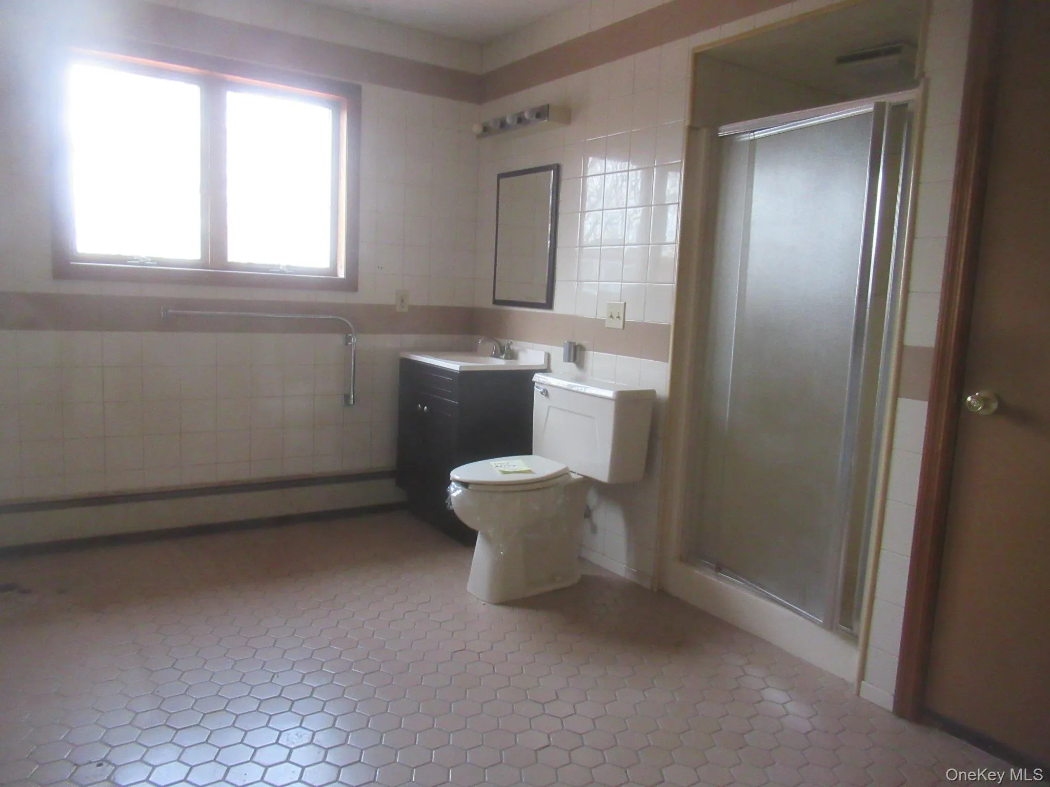 Bathroom with tile walls, vanity, a stall shower, and a baseboard heating unit Bathroom with tile walls, vanity, a stall shower, and a baseboard heating unit