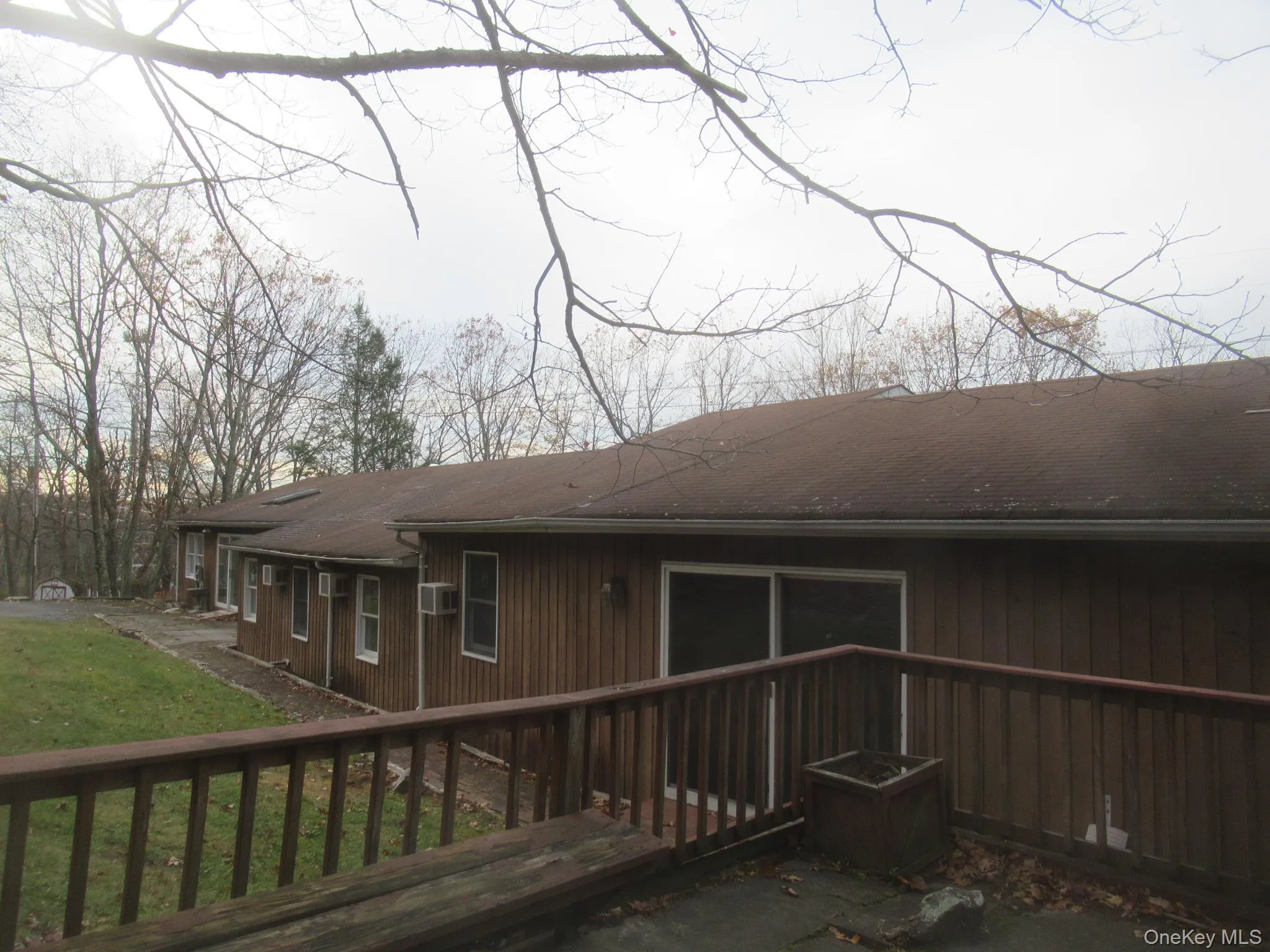 Back of house featuring a yard, a deck, and roof with shingles Back of house featuring a yard, a deck, and roof with shingles