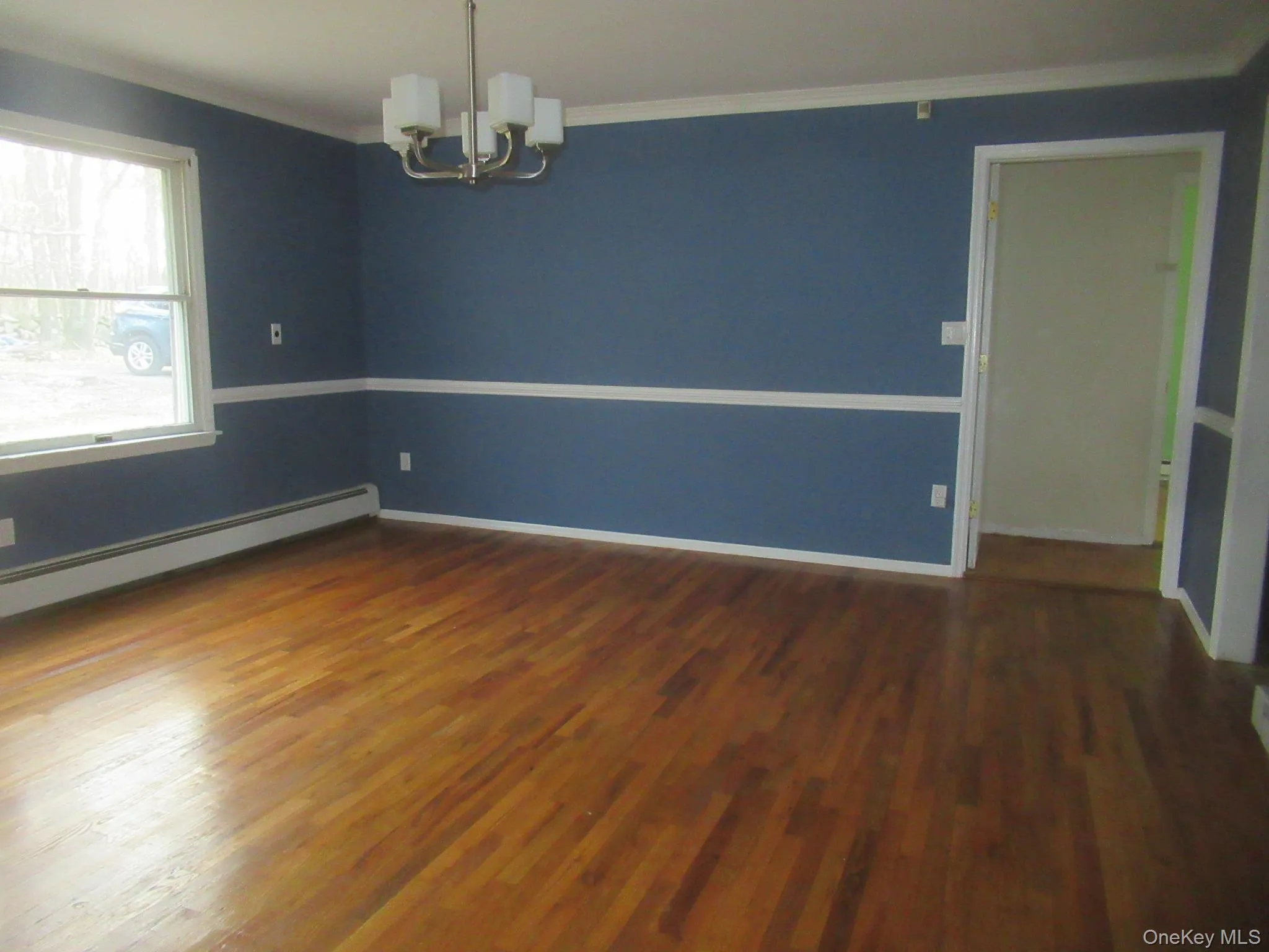 Unfurnished room with ornamental molding, a chandelier, and dark wood-style flooring Unfurnished room with ornamental molding, a chandelier, and dark wood-style flooring