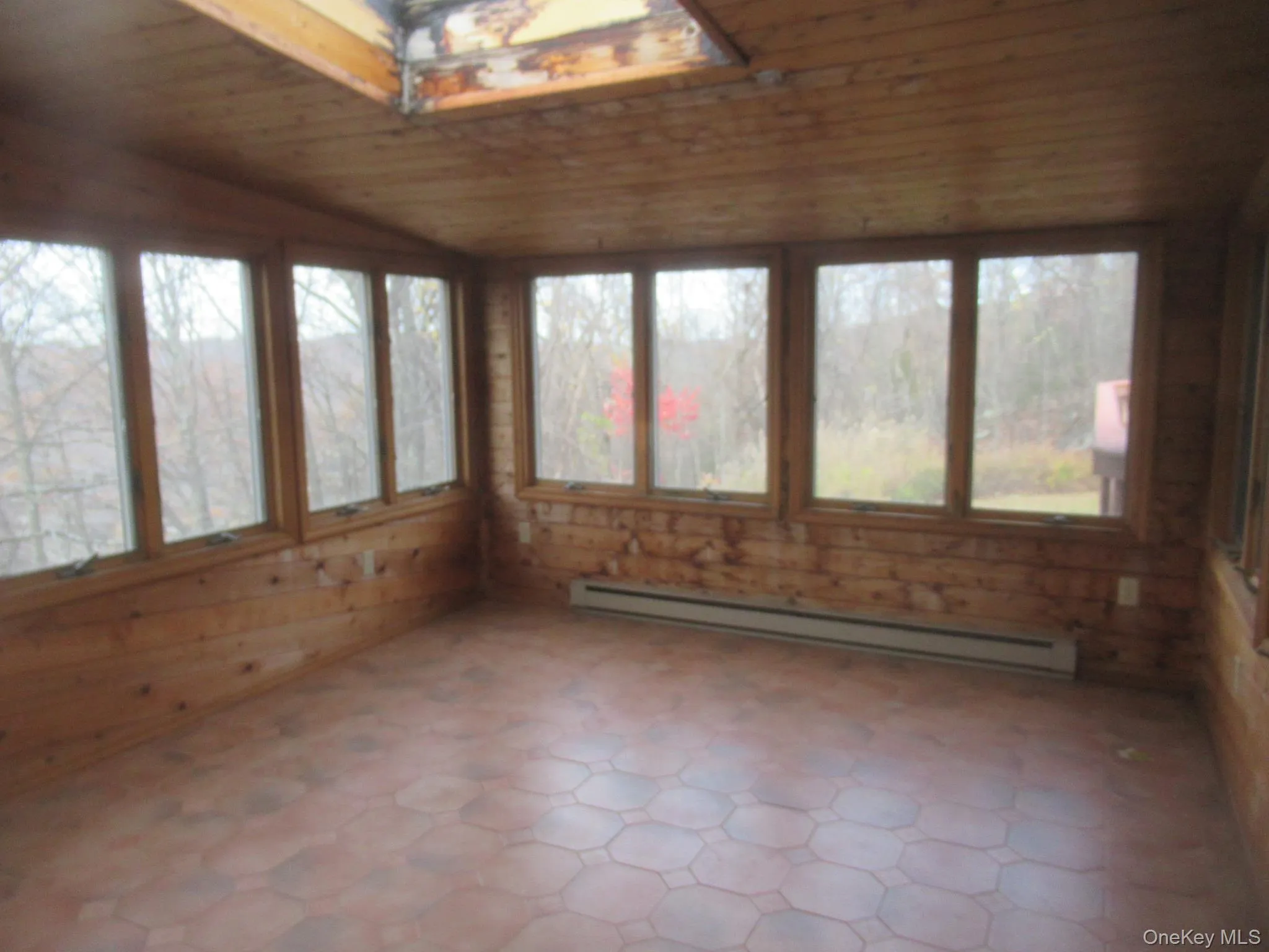Unfurnished sunroom with wood ceiling, a baseboard heating unit, vaulted ceiling, wooden walls, and tile patterned floors Unfurnished sunroom with wood ceiling, a baseboard heating unit, vaulted ceiling, wooden walls, and tile patterned floors