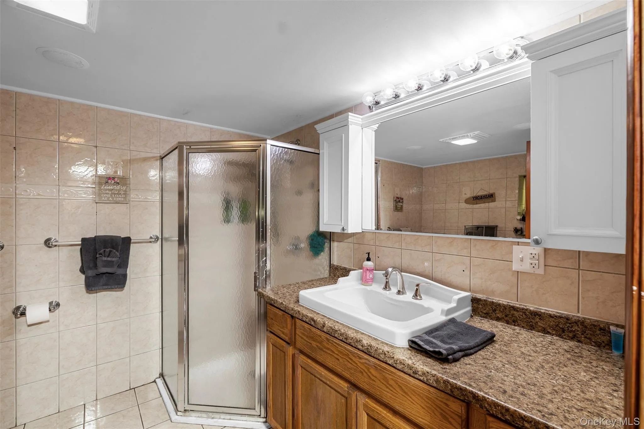 Bathroom with tile walls, vanity, a stall shower, light tile patterned flooring, and tasteful backsplash Bathroom with tile walls, vanity, a stall shower, light tile patterned flooring, and tasteful backsplash