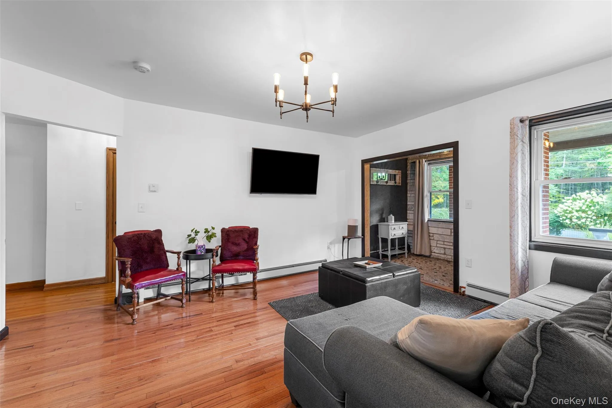 Living area with light wood finished floors, a chandelier, and a baseboard heating unit Living area with light wood finished floors, a chandelier, and a baseboard heating unit