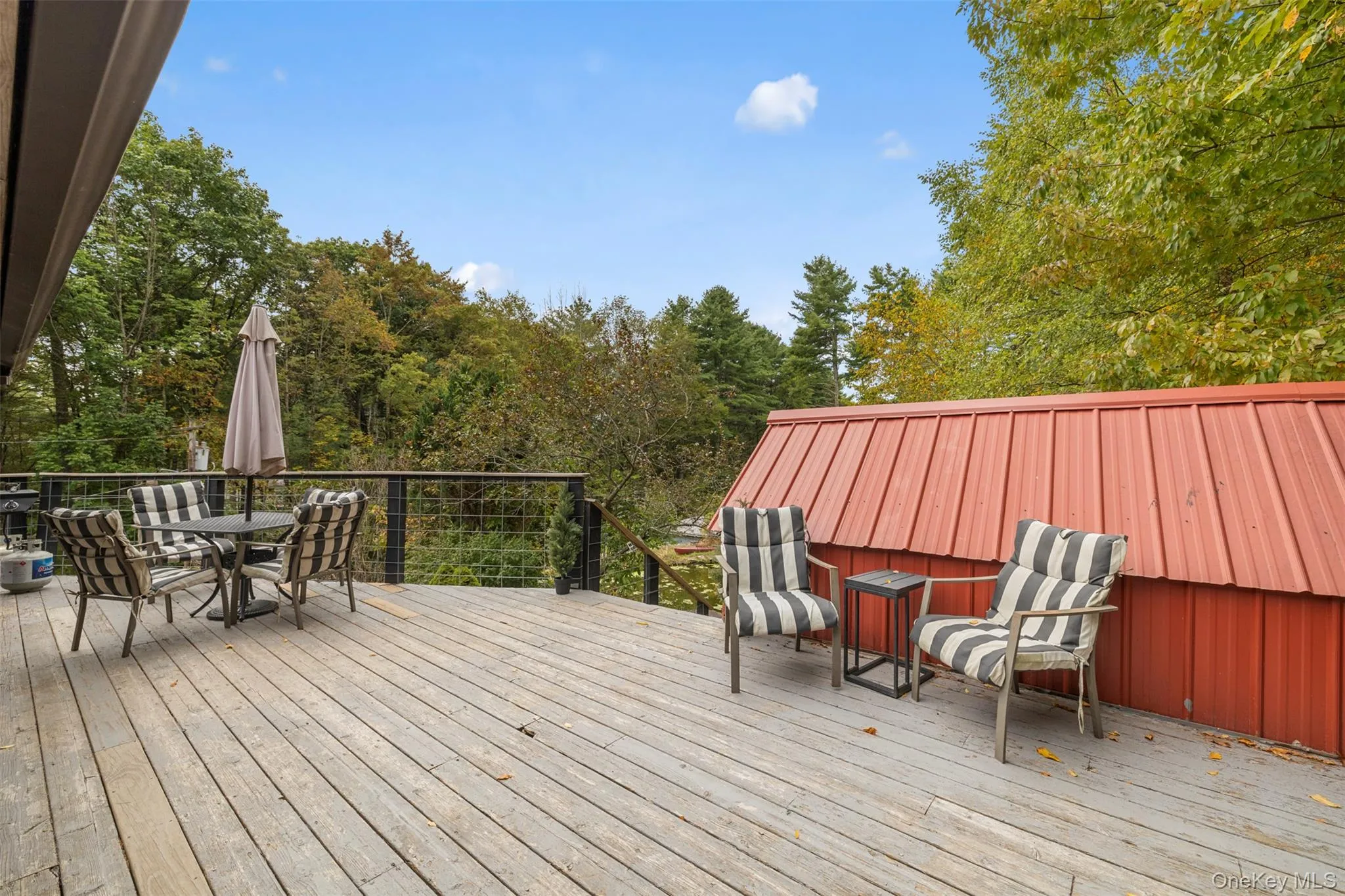 Deck with outdoor dining area and view of scattered trees Deck with outdoor dining area and view of scattered trees