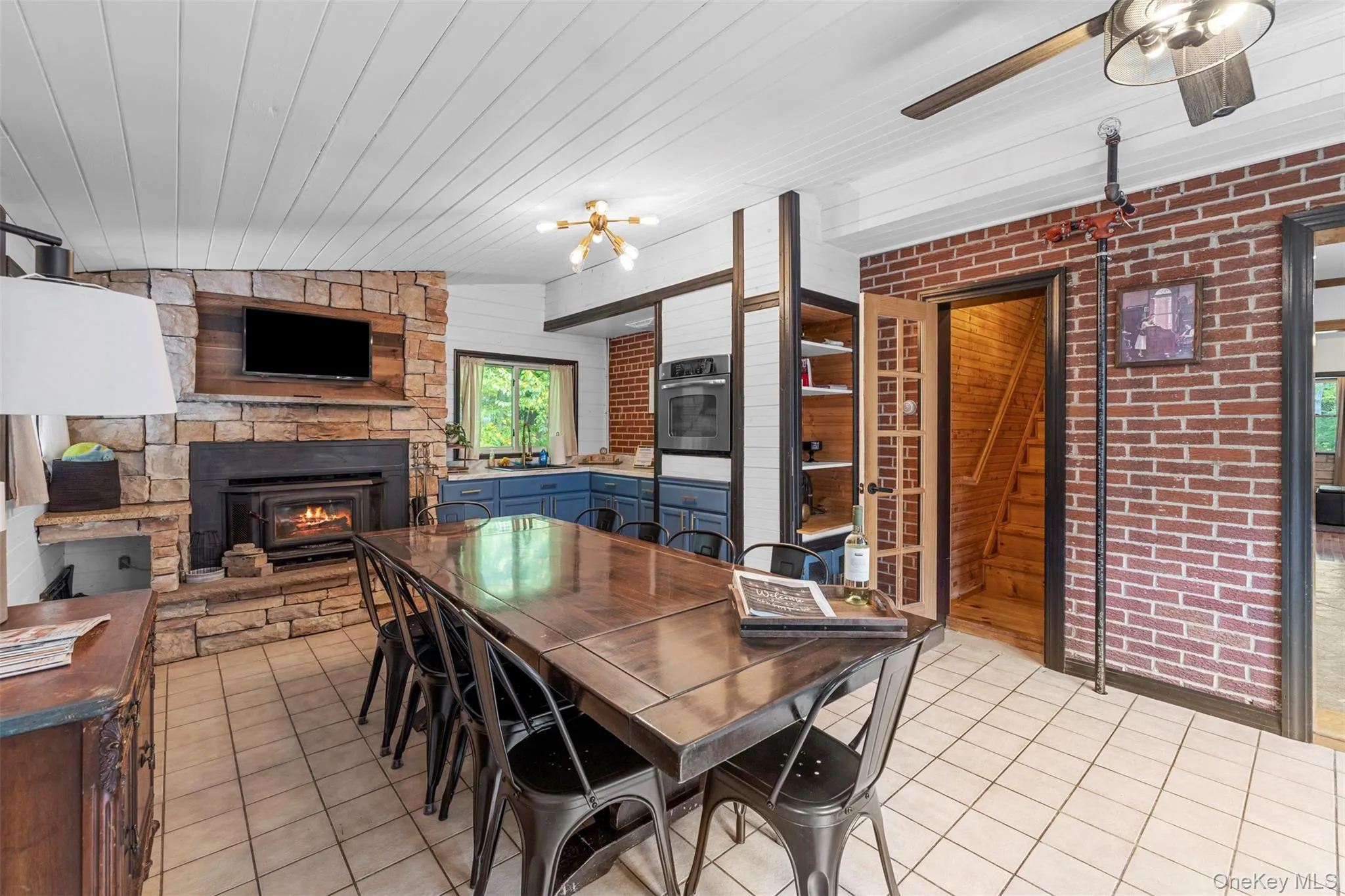 Dining area featuring brick wall, light tile patterned floors, vaulted ceiling, a fireplace, and wood ceiling Dining area featuring brick wall, light tile patterned floors, vaulted ceiling, a fireplace, and wood ceiling