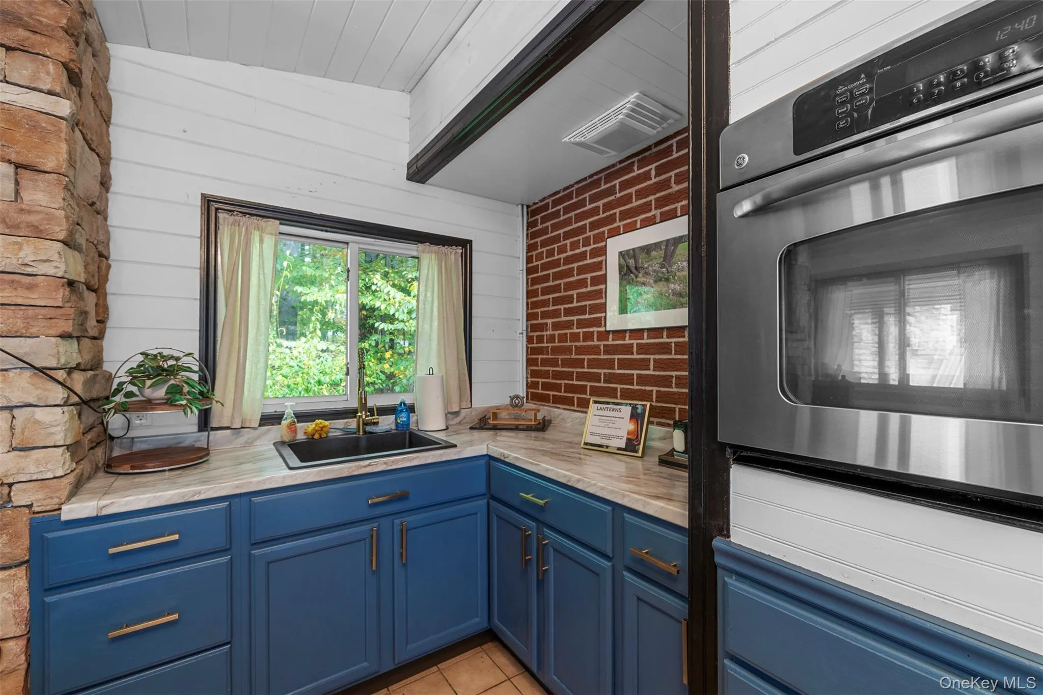 Kitchen with blue cabinetry, stainless steel oven, and light tile patterned flooring Kitchen with blue cabinetry, stainless steel oven, and light tile patterned flooring