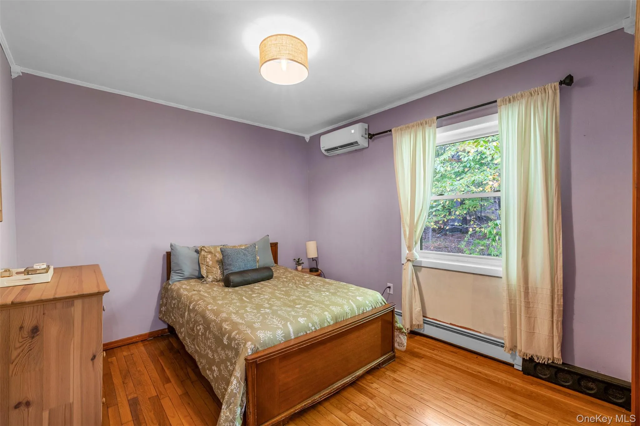 Bedroom with hardwood / wood-style floors, a baseboard radiator, a wall mounted air conditioner, and crown molding Bedroom with hardwood / wood-style floors, a baseboard radiator, a wall mounted air conditioner, and crown molding