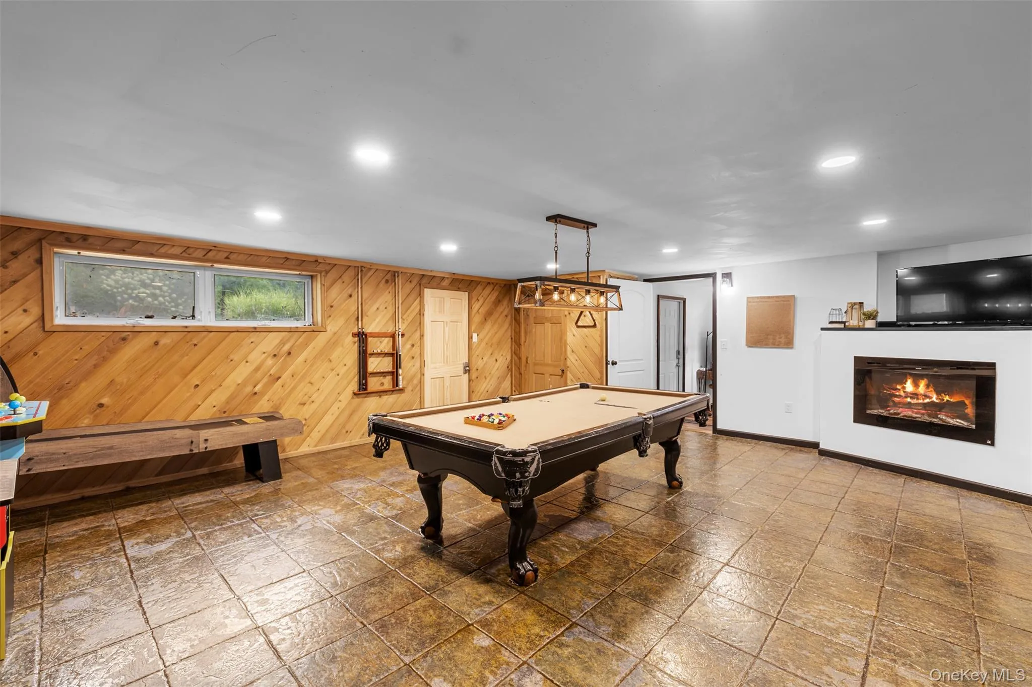 Recreation room featuring a glass covered fireplace, billiards table, recessed lighting, and wooden walls Recreation room featuring a glass covered fireplace, billiards table, recessed lighting, and wooden walls