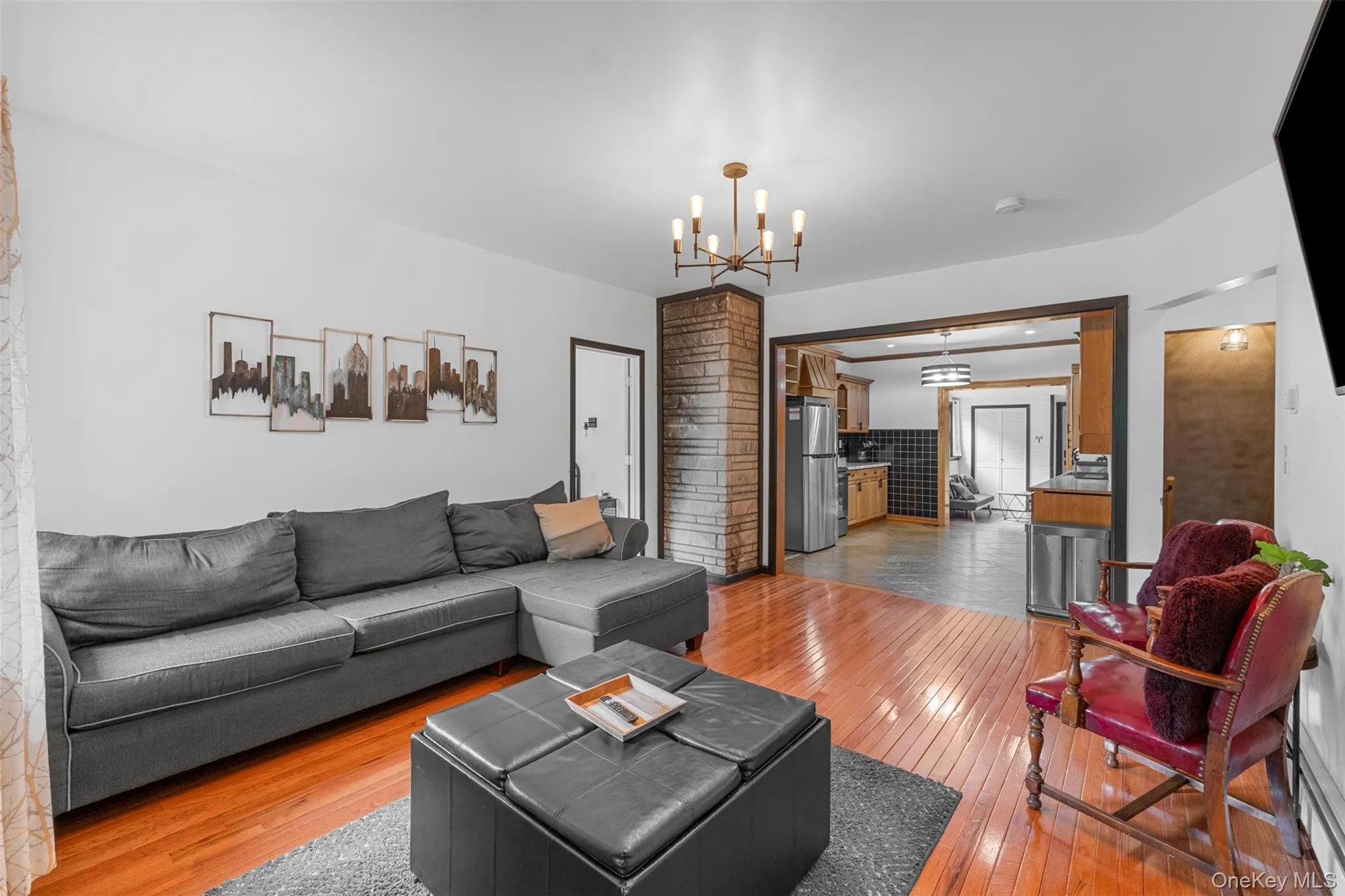 Living room with light wood-style flooring, a chandelier, and baseboard heating Living room with light wood-style flooring, a chandelier, and baseboard heating