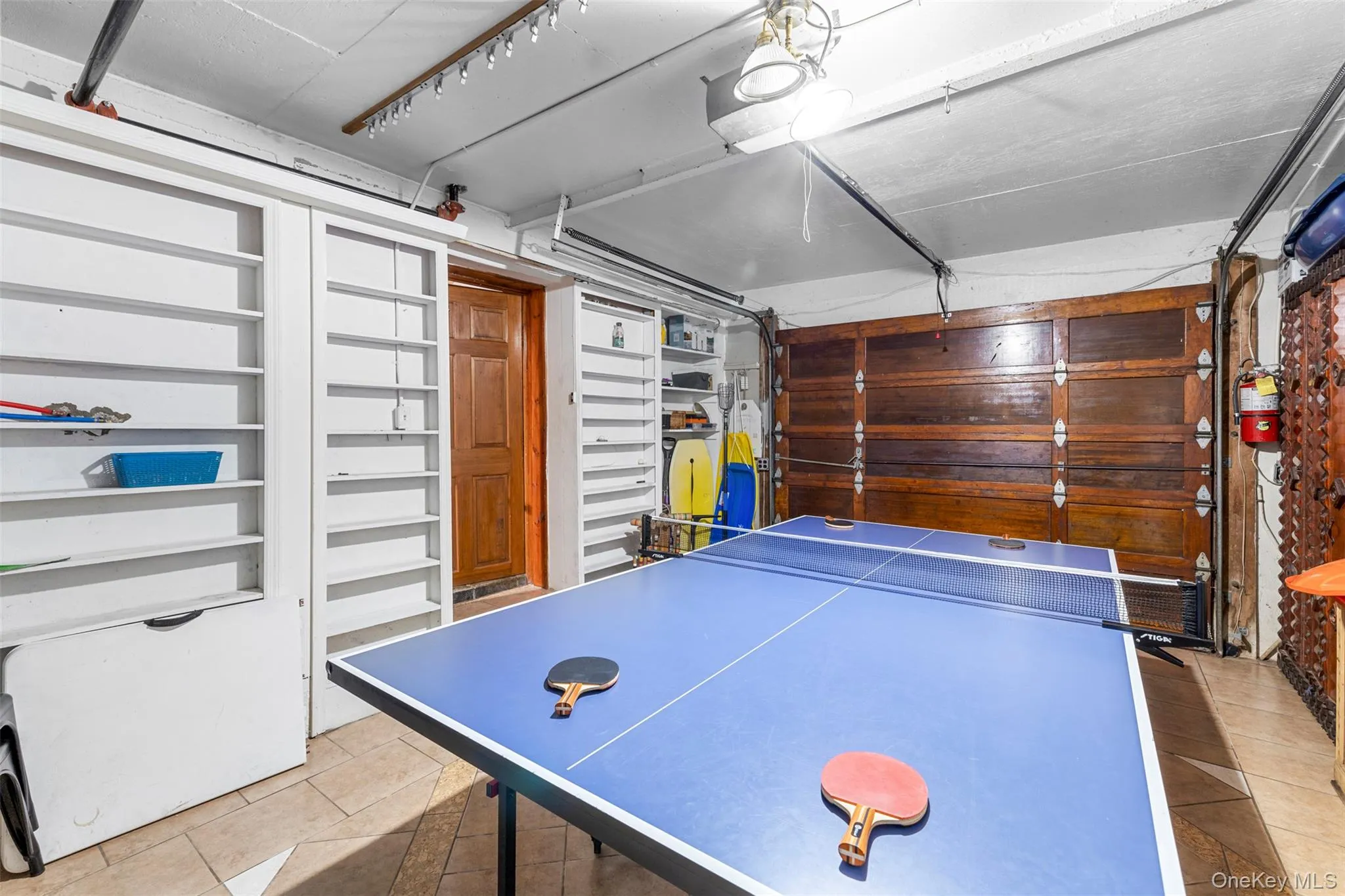 Recreation room featuring a garage and light tile patterned floors Recreation room featuring a garage and light tile patterned floors