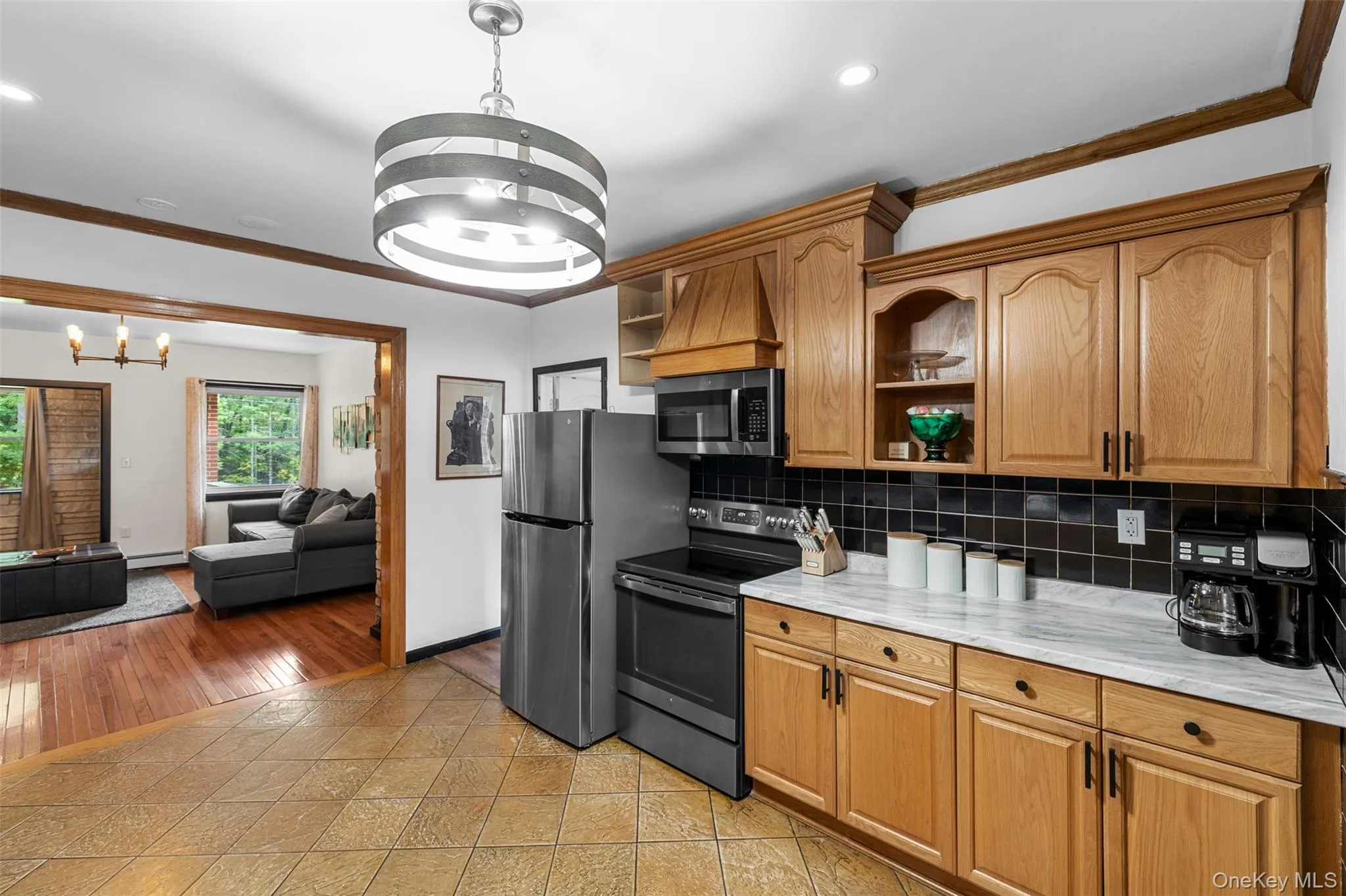 Kitchen with ornamental molding, open shelves, decorative backsplash, stainless steel appliances, and a chandelier Kitchen with ornamental molding, open shelves, decorative backsplash, stainless steel appliances, and a chandelier