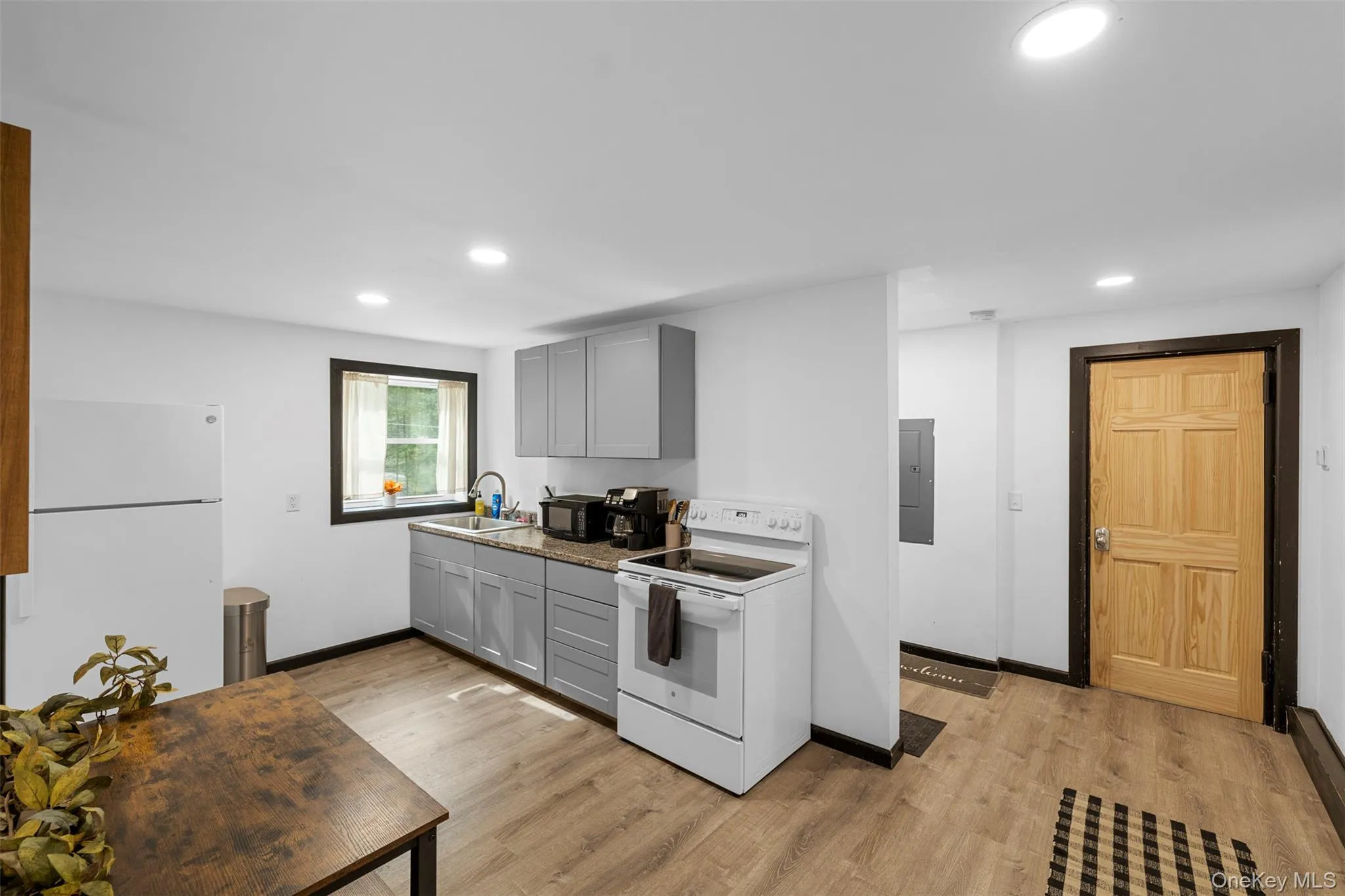 Kitchen with gray cabinets, white appliances, light wood-type flooring, and recessed lighting Kitchen with gray cabinets, white appliances, light wood-type flooring, and recessed lighting