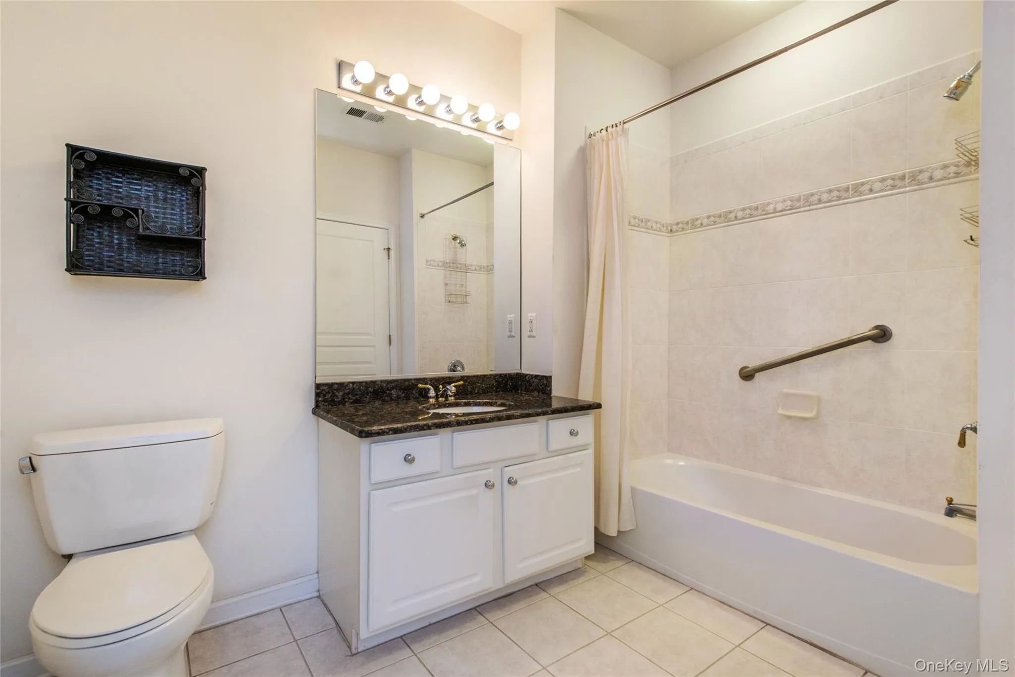 Bathroom featuring a white vanity with dark countertop, an integrated sink, and an overhead strip light fixture Bathroom featuring a white vanity with dark countertop, an integrated sink, and an overhead strip light fixture