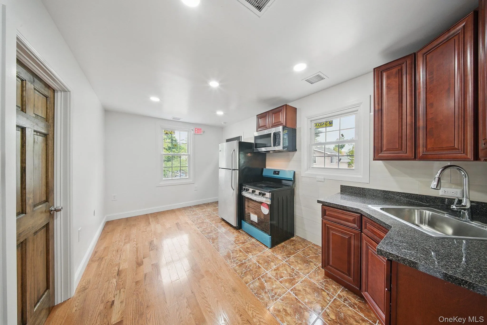 Kitchen featuring stainless steel appliances, a sink, light wood-type flooring, recessed lighting, and granite countertops Kitchen featuring stainless steel appliances, a sink, light wood-type flooring, recessed lighting, and granite countertops