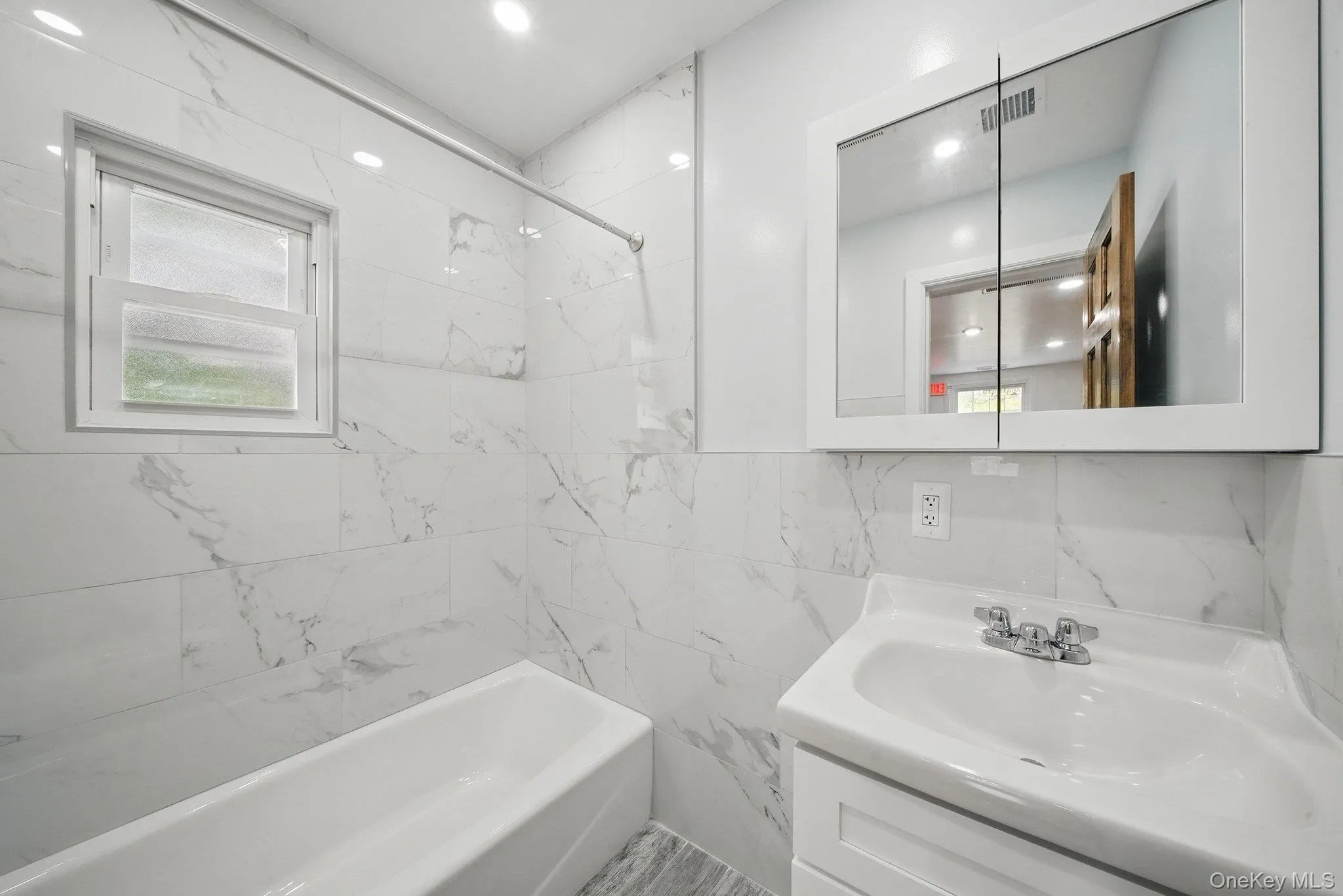 Full bath with vanity, bathtub / shower combination, and tile walls Full bath with vanity, bathtub / shower combination, and tile walls