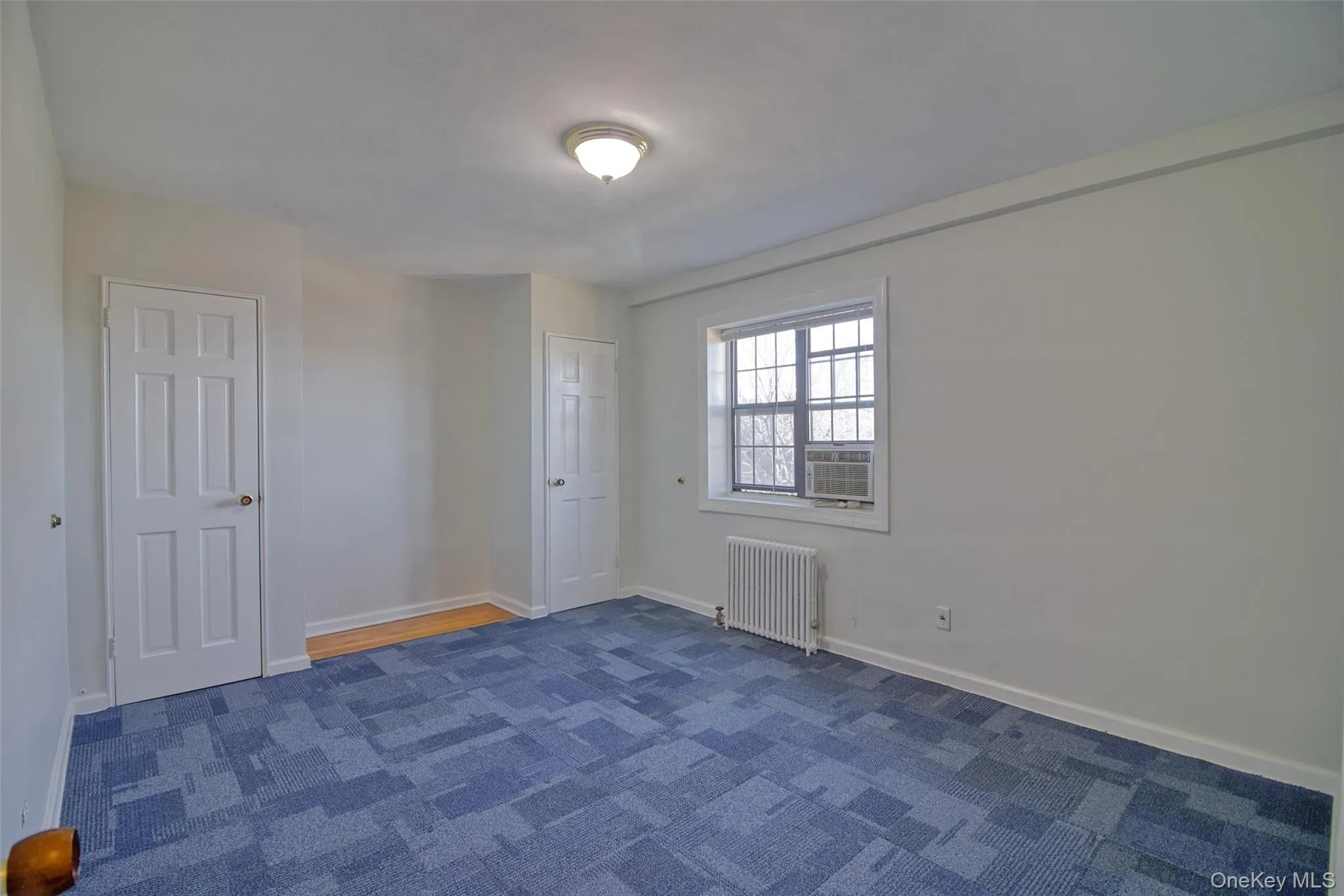 Bedroom with baseboards, cooling unit, and radiator heating unit Bedroom with baseboards, cooling unit, and radiator heating unit