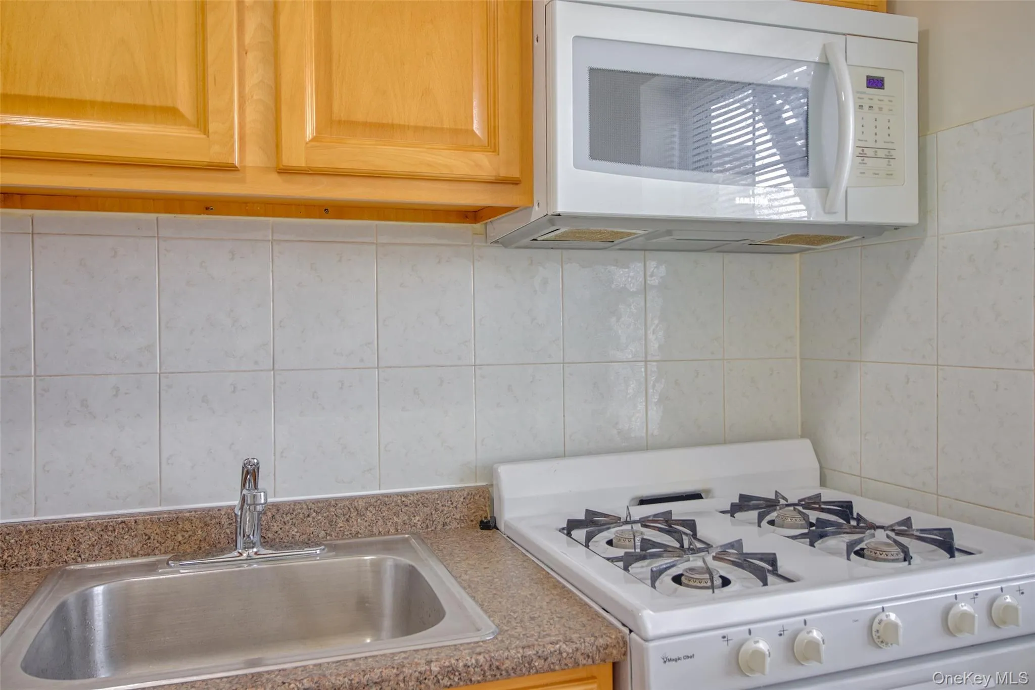 Kitchen featuring white appliances, tasteful backsplash, tile walls, and a sink Kitchen featuring white appliances, tasteful backsplash, tile walls, and a sink