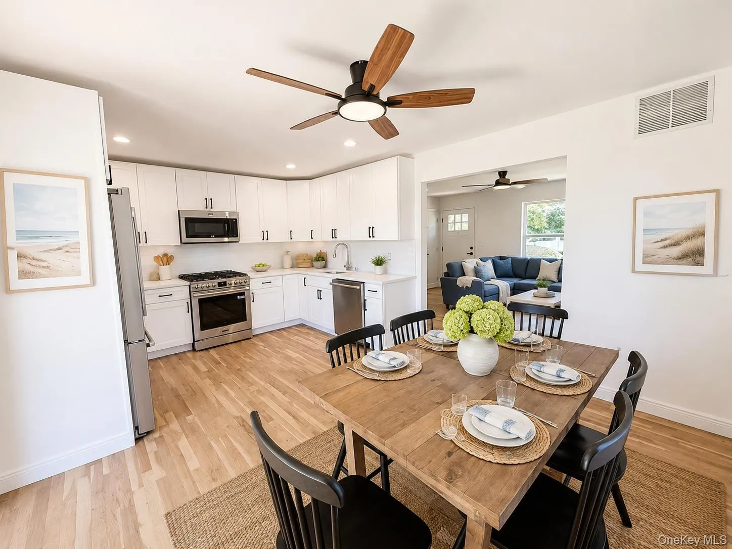 Kitchen and dining area featuring wood-finish flooring, white cabinetry, stainless steel appliances, and recessed lighting Kitchen and dining area featuring wood-finish flooring, white cabinetry, stainless steel appliances, and recessed lighting