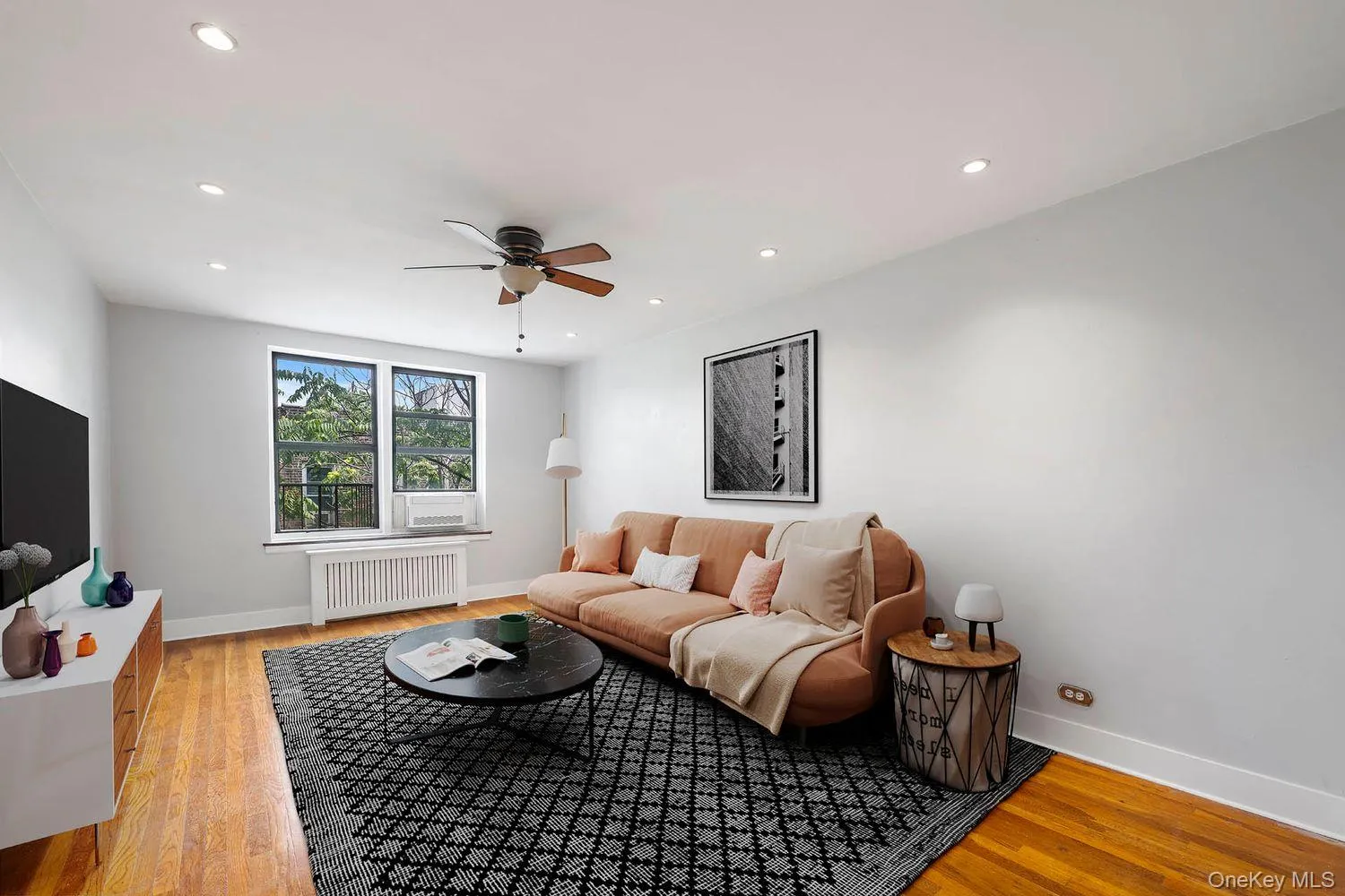 Living area featuring radiator heating unit, ceiling fan, light wood-type flooring, and recessed lighting Living area featuring radiator heating unit, ceiling fan, light wood-type flooring, and recessed lighting