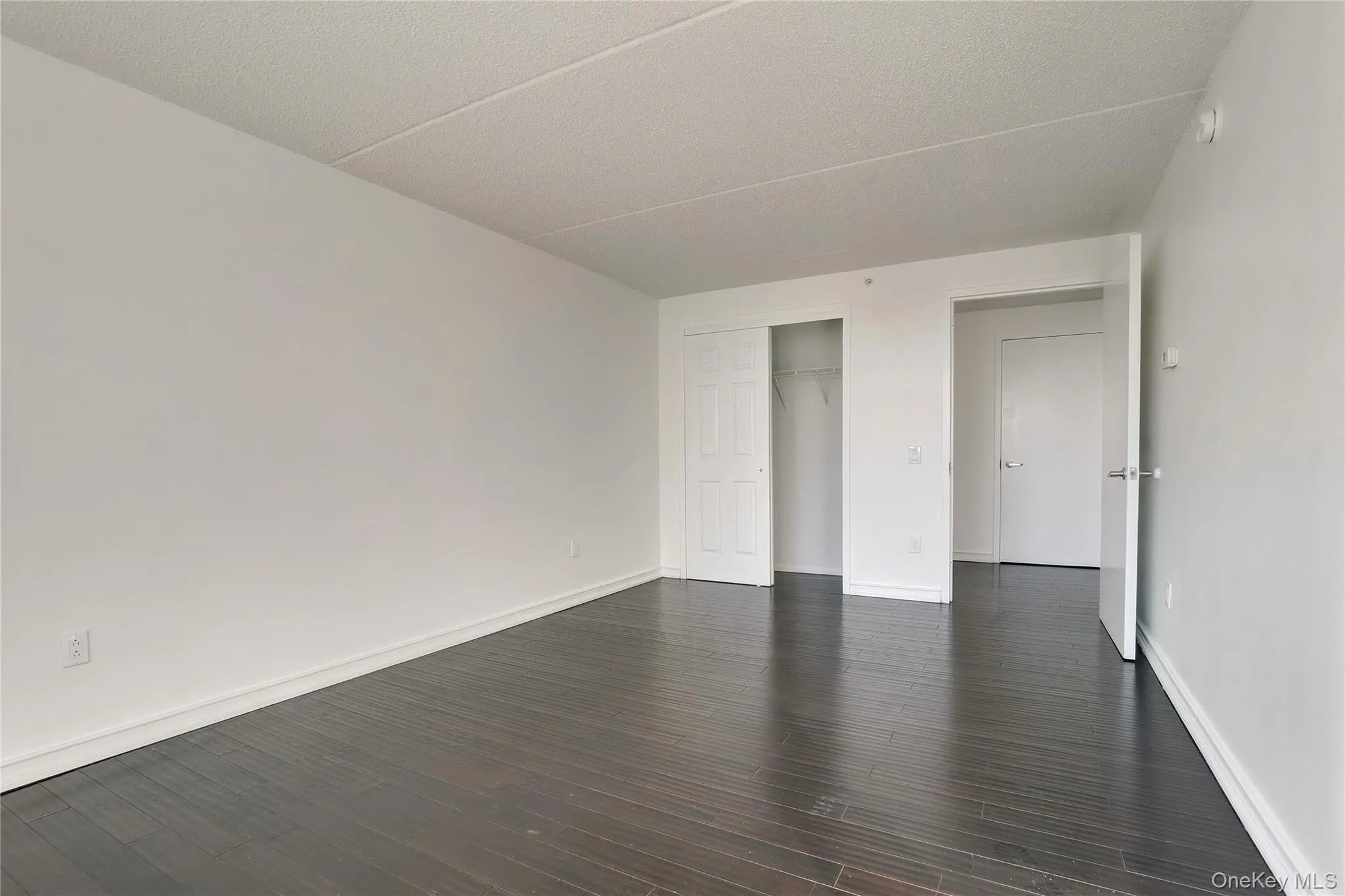 Spare room featuring dark wood-style flooring and a textured ceiling Spare room featuring dark wood-style flooring and a textured ceiling