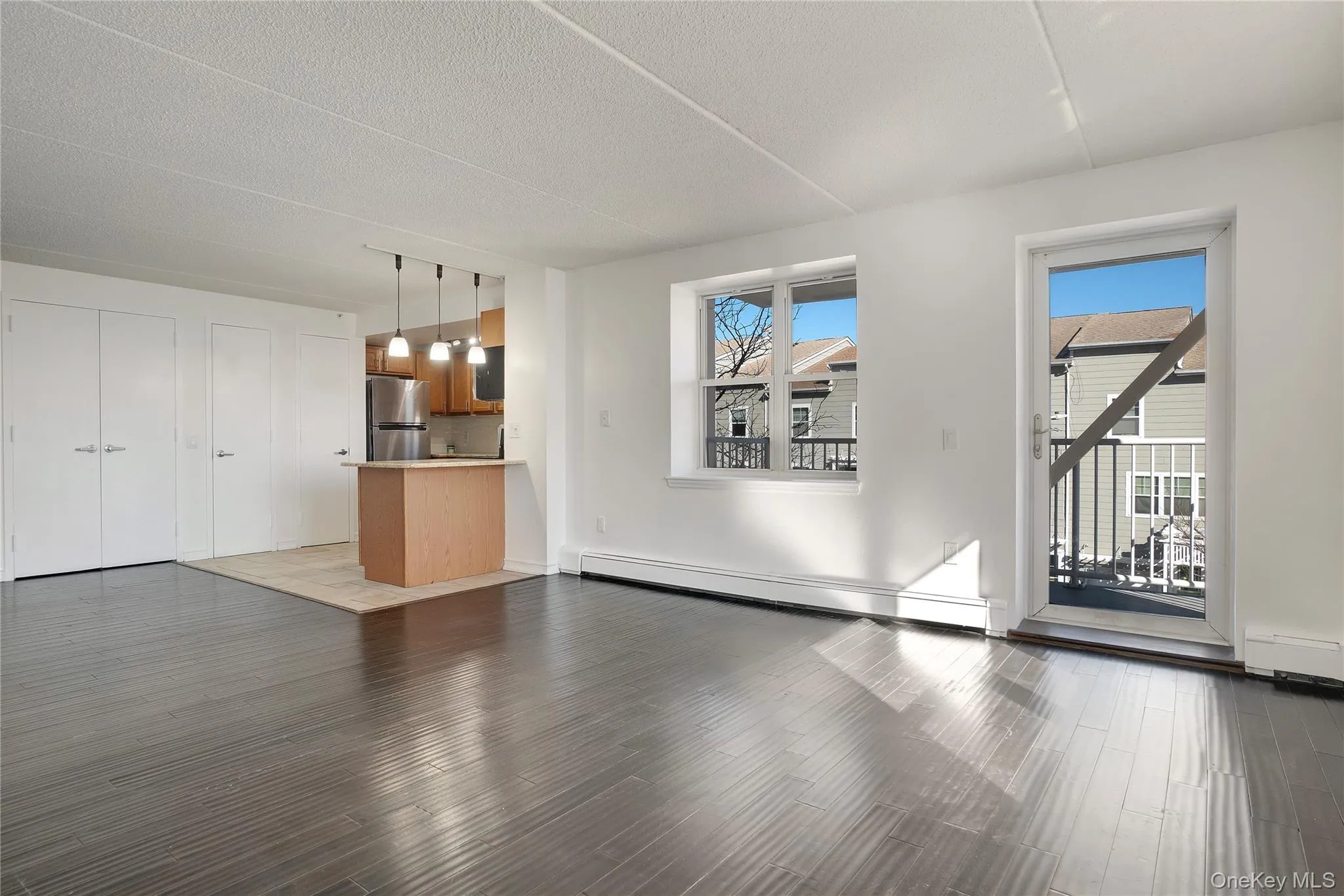 Unfurnished living room featuring wood finished floors, a baseboard radiator, and a textured ceiling Unfurnished living room featuring wood finished floors, a baseboard radiator, and a textured ceiling