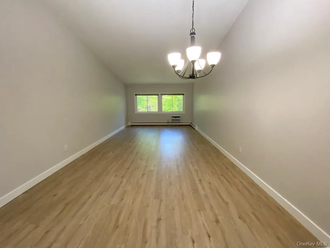 Spacious, open living/dining room featuring vaulted ceilings, a contemporary chandelier, and wood-like flooring Spacious, open living/dining room featuring vaulted ceilings, a contemporary chandelier, and wood-like flooring