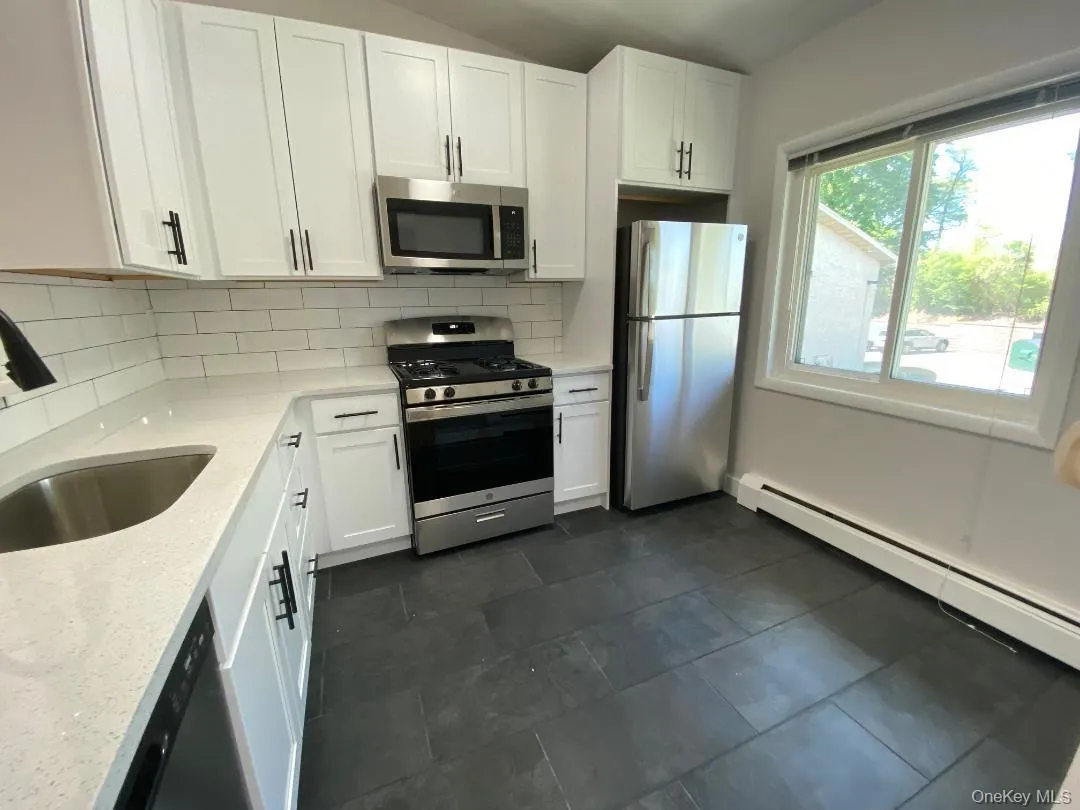 Beautifully just renovated eat in kitchen featuring lots white shaker cabinetry with dark hardware, quartz counters, stainless steel appliances, subway tile backsplash, and pretty tile floor. Beautifully just renovated eat in kitchen featuring lots white shaker cabinetry with dark hardware, quartz counters, stainless steel appliances, subway tile backsplash, and pretty tile floor.