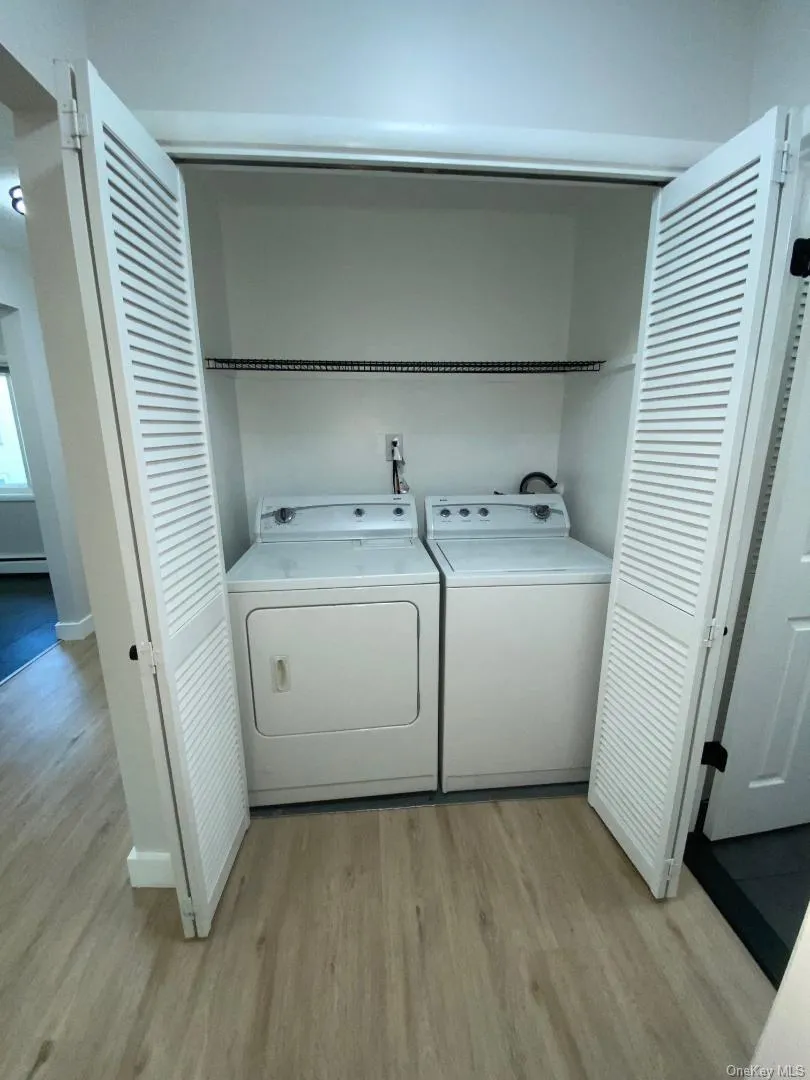 Dedicated laundry closet featuring louvered bi-fold doors, a full size washer and dryer, and a wire storage shelf. Dedicated laundry closet featuring louvered bi-fold doors, a full size washer and dryer, and a wire storage shelf.