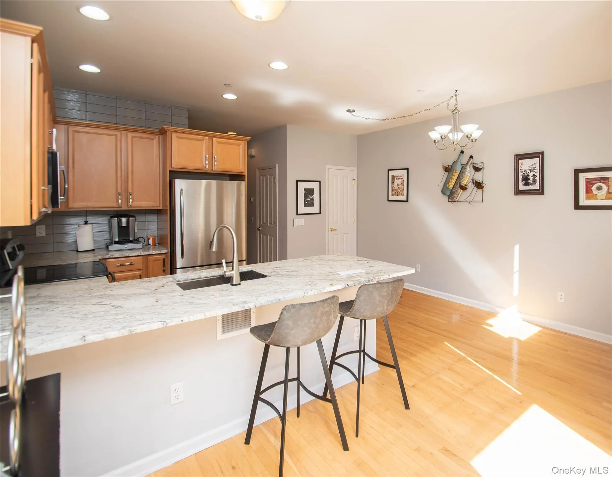 Kitchen with recessed lighting, a peninsula, decorative backsplash, appliances with stainless steel finishes, and light wood-type flooring Kitchen with recessed lighting, a peninsula, decorative backsplash, appliances with stainless steel finishes, and light wood-type flooring