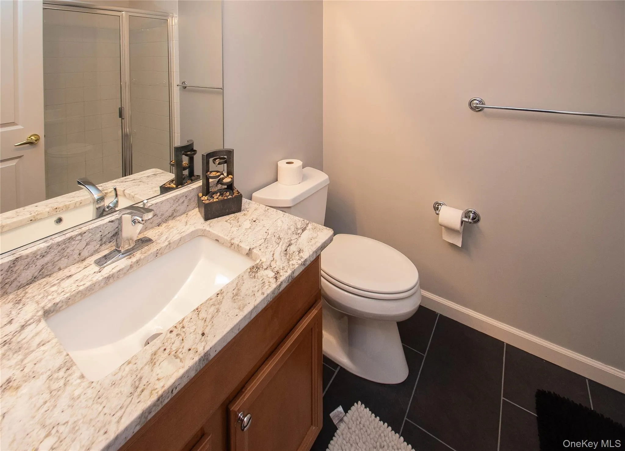Bathroom with vanity, a shower stall, and dark tile patterned floors Bathroom with vanity, a shower stall, and dark tile patterned floors