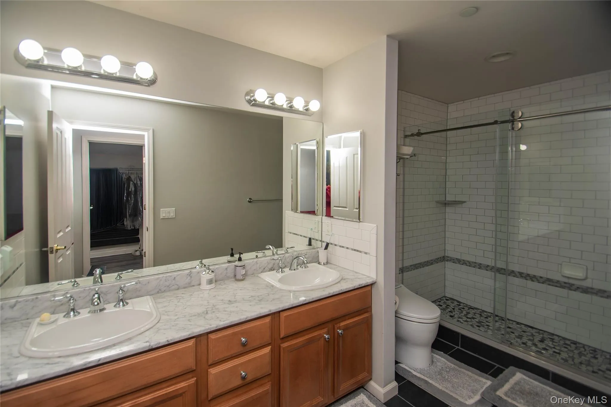 Full bathroom with a stall shower, double vanity, and dark tile patterned flooring Full bathroom with a stall shower, double vanity, and dark tile patterned flooring