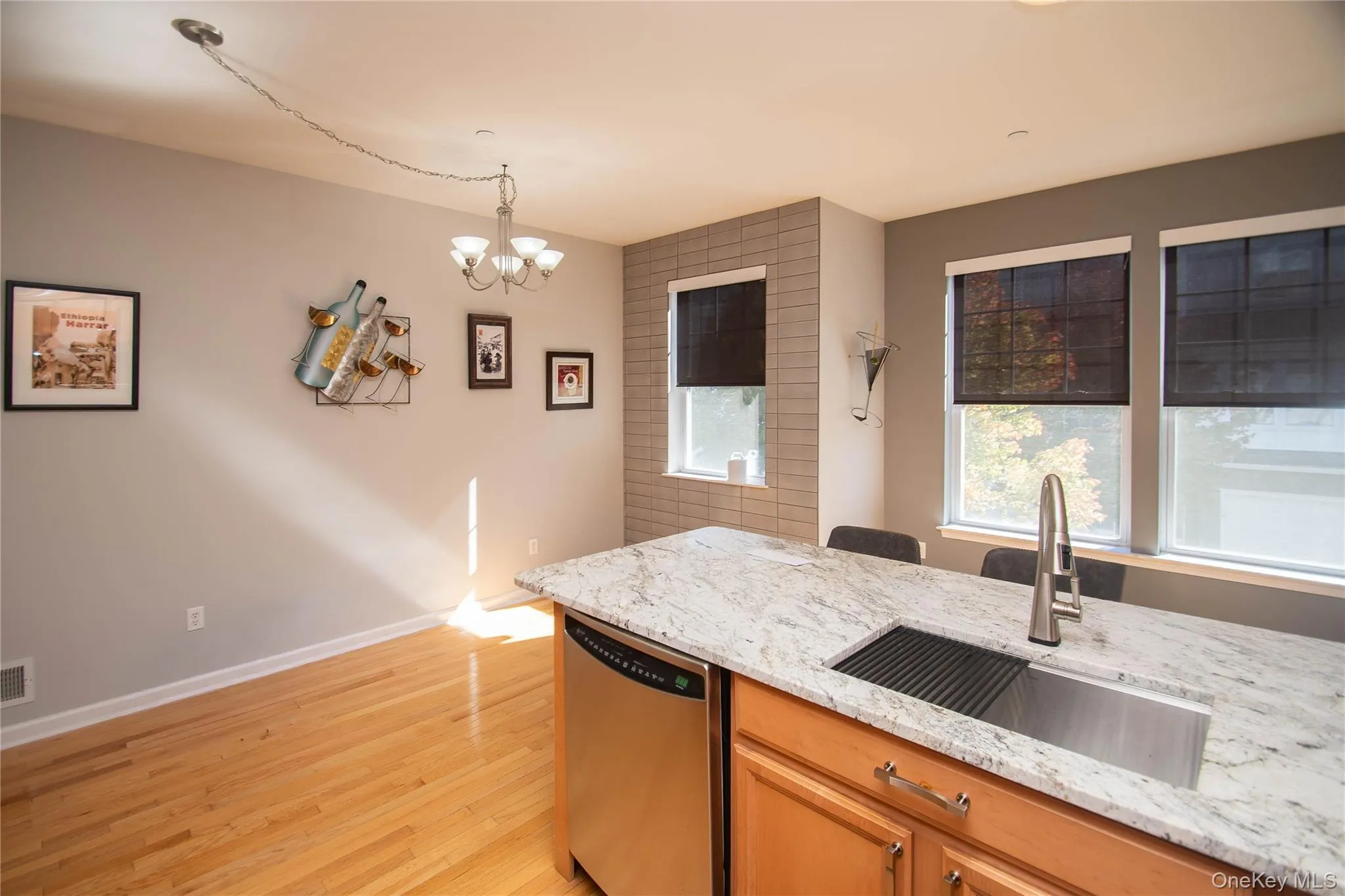Kitchen with dishwasher, hanging light fixtures, healthy amount of natural light, and light wood-style flooring Kitchen with dishwasher, hanging light fixtures, healthy amount of natural light, and light wood-style flooring