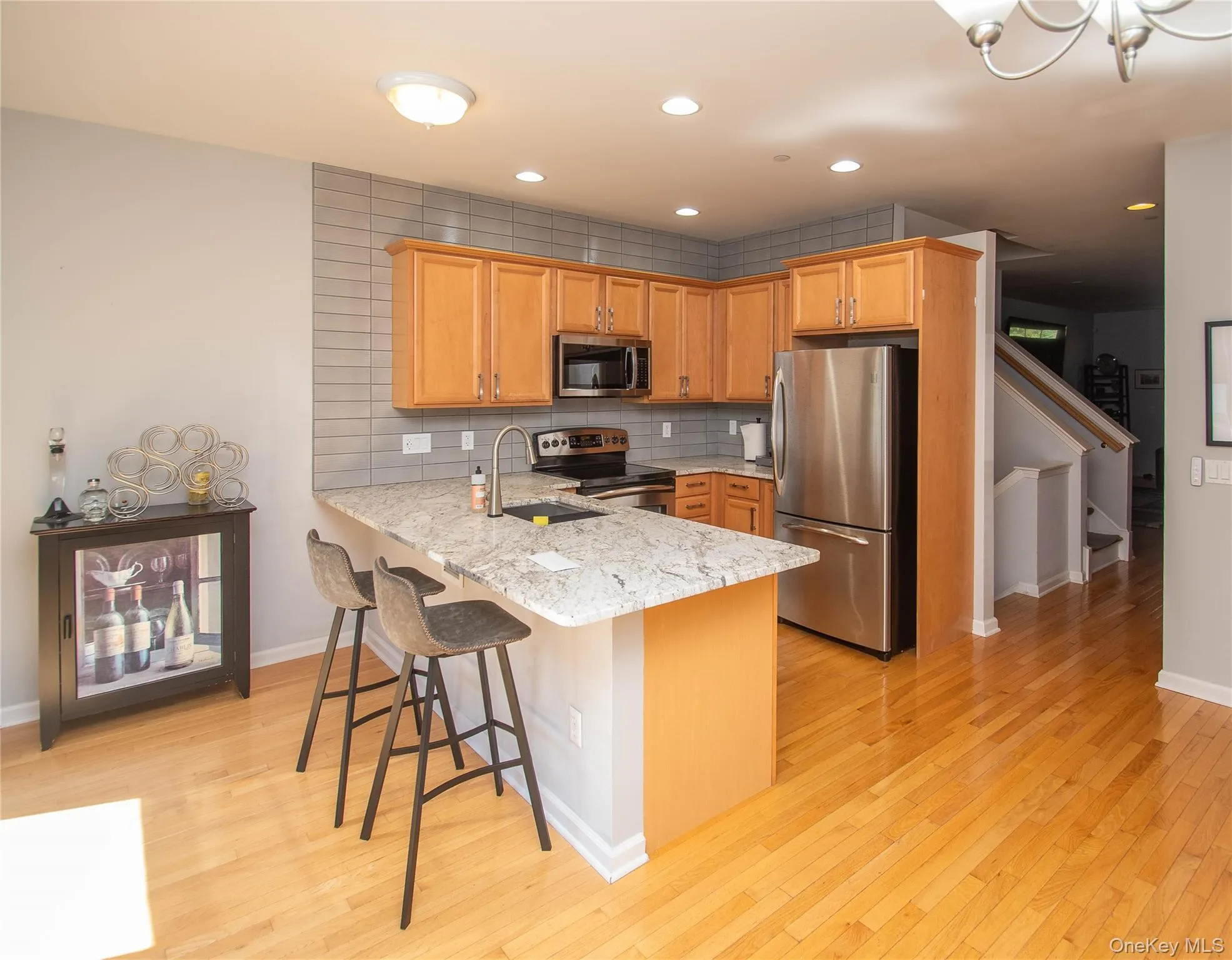Kitchen with tasteful backsplash, stainless steel appliances, light stone counters, a peninsula, and recessed lighting Kitchen with tasteful backsplash, stainless steel appliances, light stone counters, a peninsula, and recessed lighting