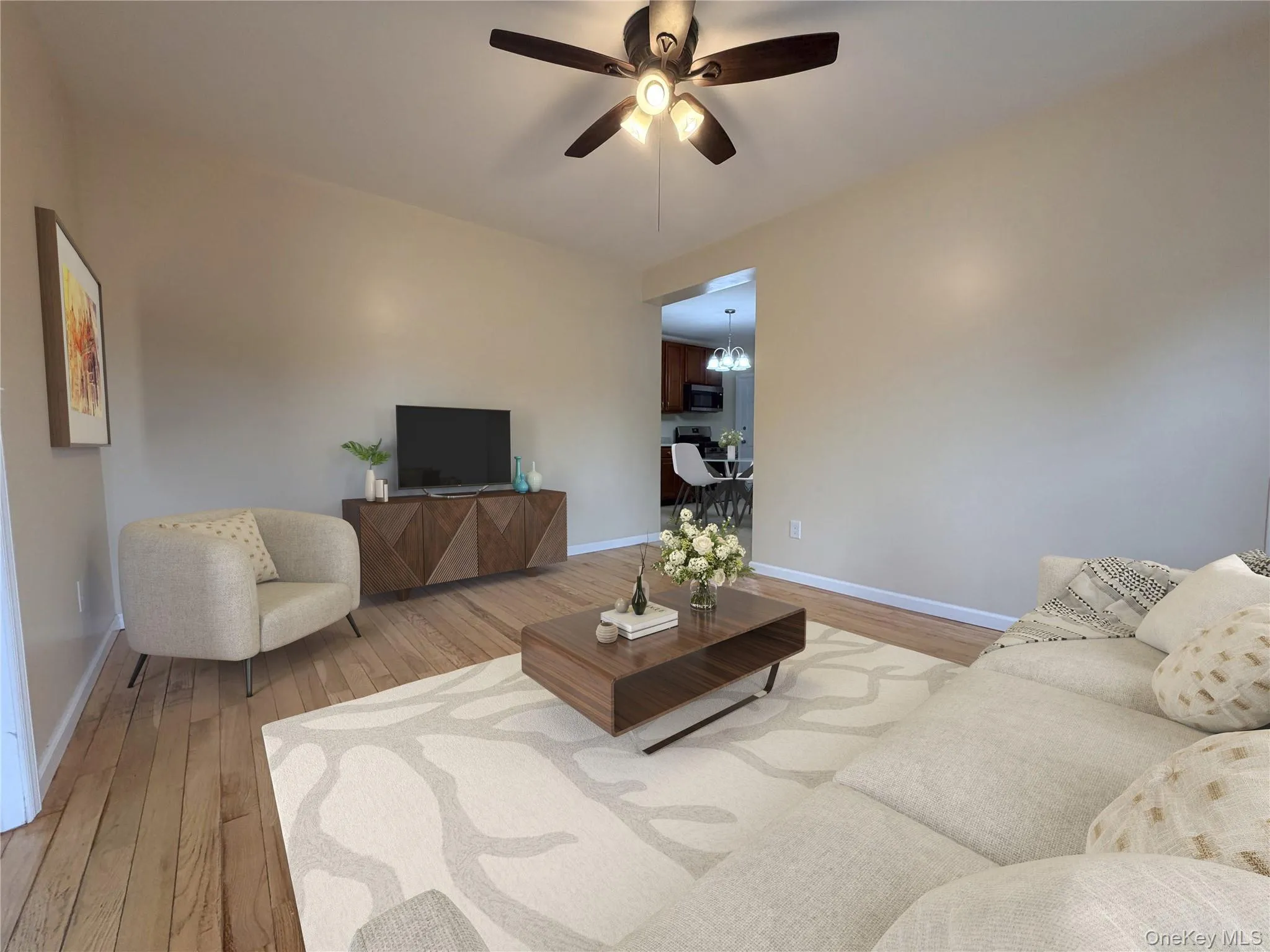 Living area featuring wood-finish flooring, a ceiling fan with integrated lighting, and neutral wall tones Living area featuring wood-finish flooring, a ceiling fan with integrated lighting, and neutral wall tones