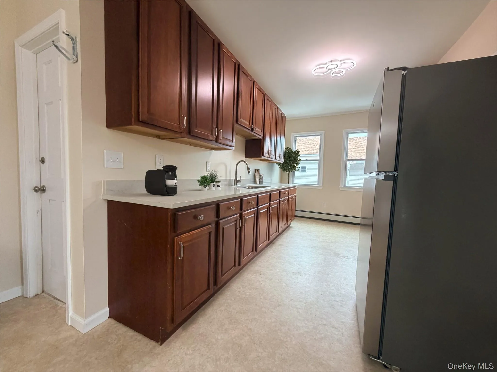 Kitchen featuring wood-finish cabinetry, light countertops, and a stainless steel refrigerator Kitchen featuring wood-finish cabinetry, light countertops, and a stainless steel refrigerator