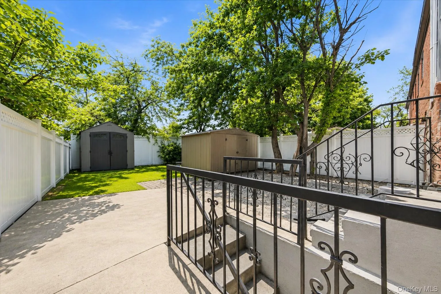 Backyard featuring a concrete patio, manicured lawn, and two storage sheds Backyard featuring a concrete patio, manicured lawn, and two storage sheds