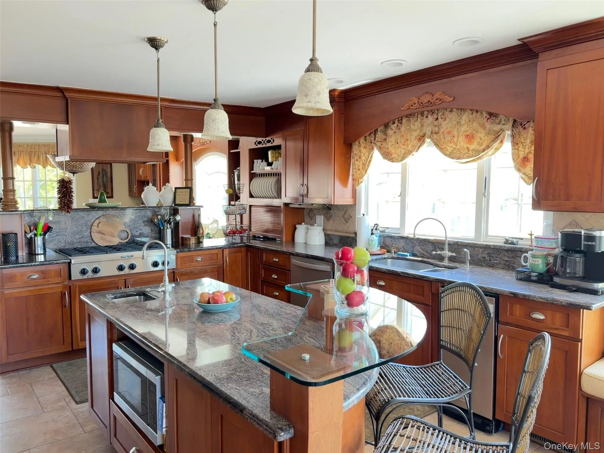 Well-appointed kitchen featuring a large central island with integrated sink, built-in microwave, and a curved glass breakfast bar Well-appointed kitchen featuring a large central island with integrated sink, built-in microwave, and a curved glass breakfast bar