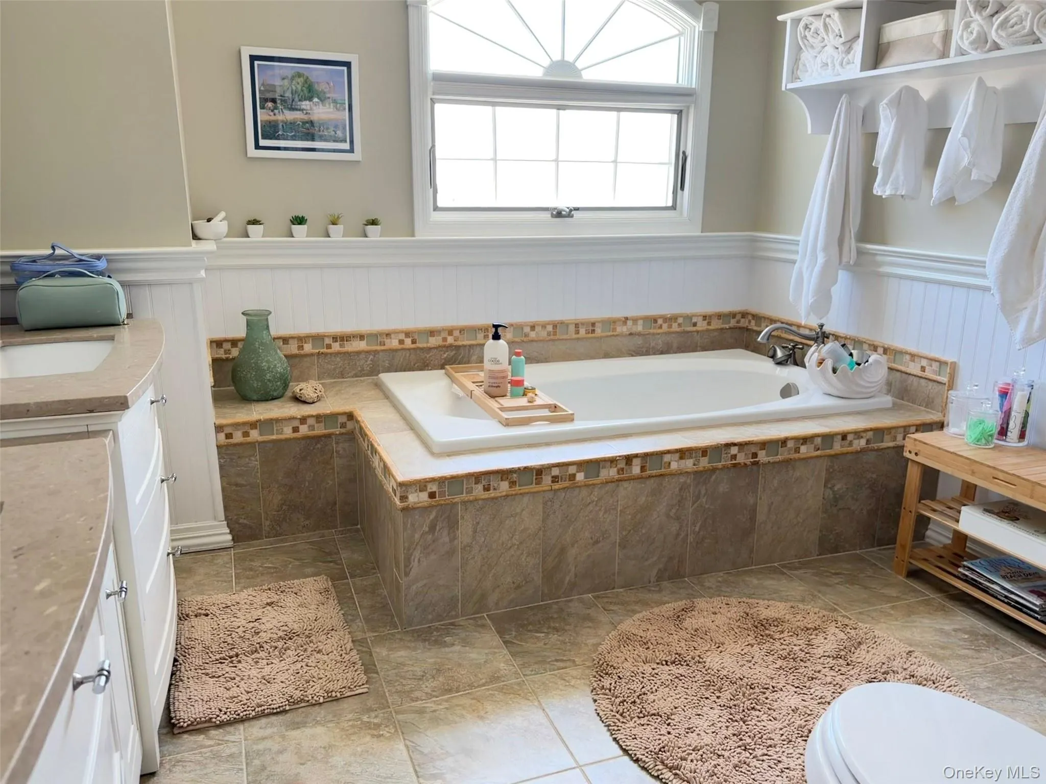 Spacious bathroom featuring a built-in soaking tub with tiled surround and decorative mosaic border Spacious bathroom featuring a built-in soaking tub with tiled surround and decorative mosaic border