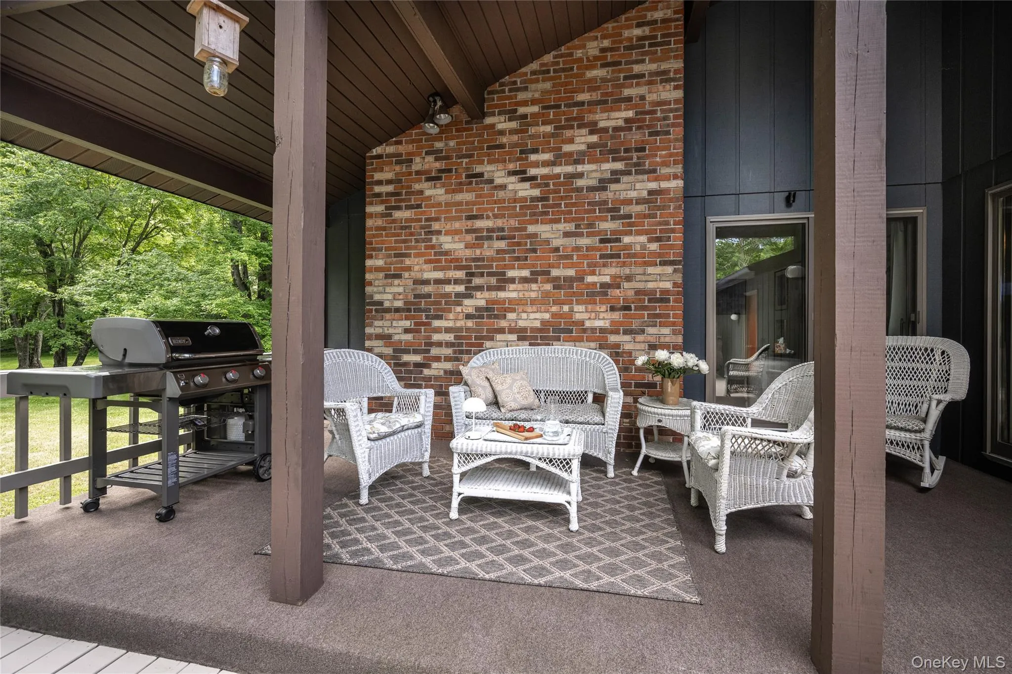 Covered outdoor patio featuring brick siding and dark-toned board and batten Covered outdoor patio featuring brick siding and dark-toned board and batten
