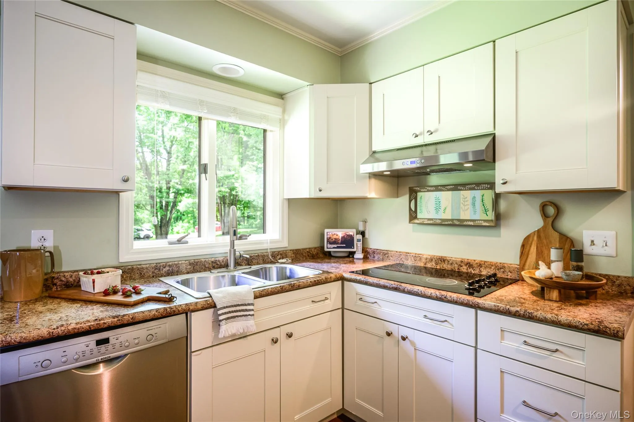 Kitchen featuring light cabinetry, a double basin stainless steel sink, a stainless steel dishwasher, a built-in cooktop, and a stainless steel range hood Kitchen featuring light cabinetry, a double basin stainless steel sink, a stainless steel dishwasher, a built-in cooktop, and a stainless steel range hood