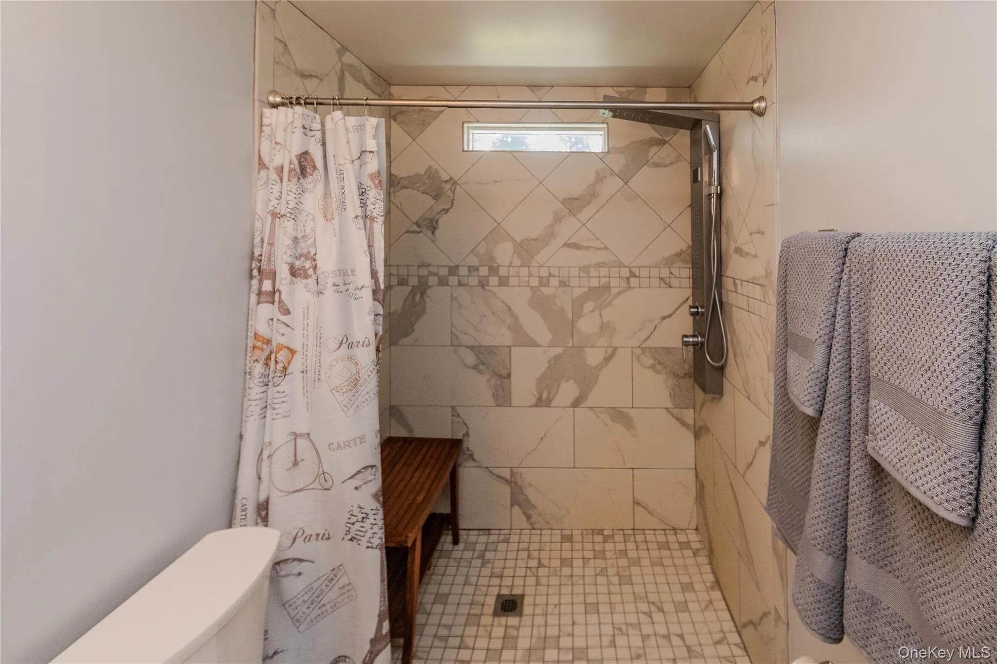Walk-in shower with full tile surround, decorative accent banding, and a horizontal window Walk-in shower with full tile surround, decorative accent banding, and a horizontal window