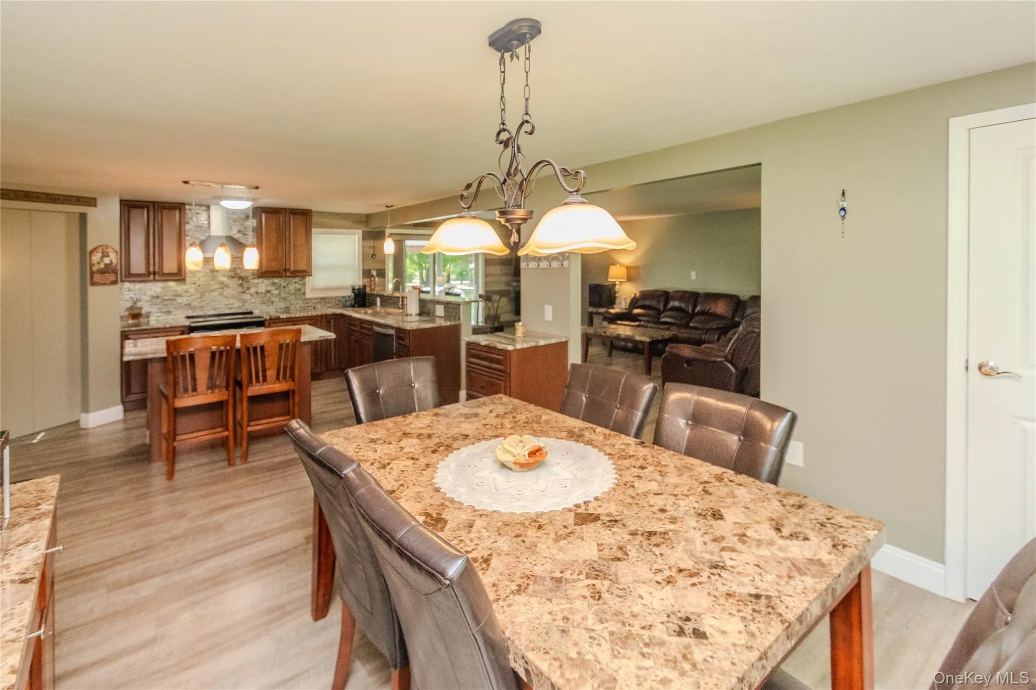 Dining area featuring wood-finish flooring and a decorative chandelier Dining area featuring wood-finish flooring and a decorative chandelier