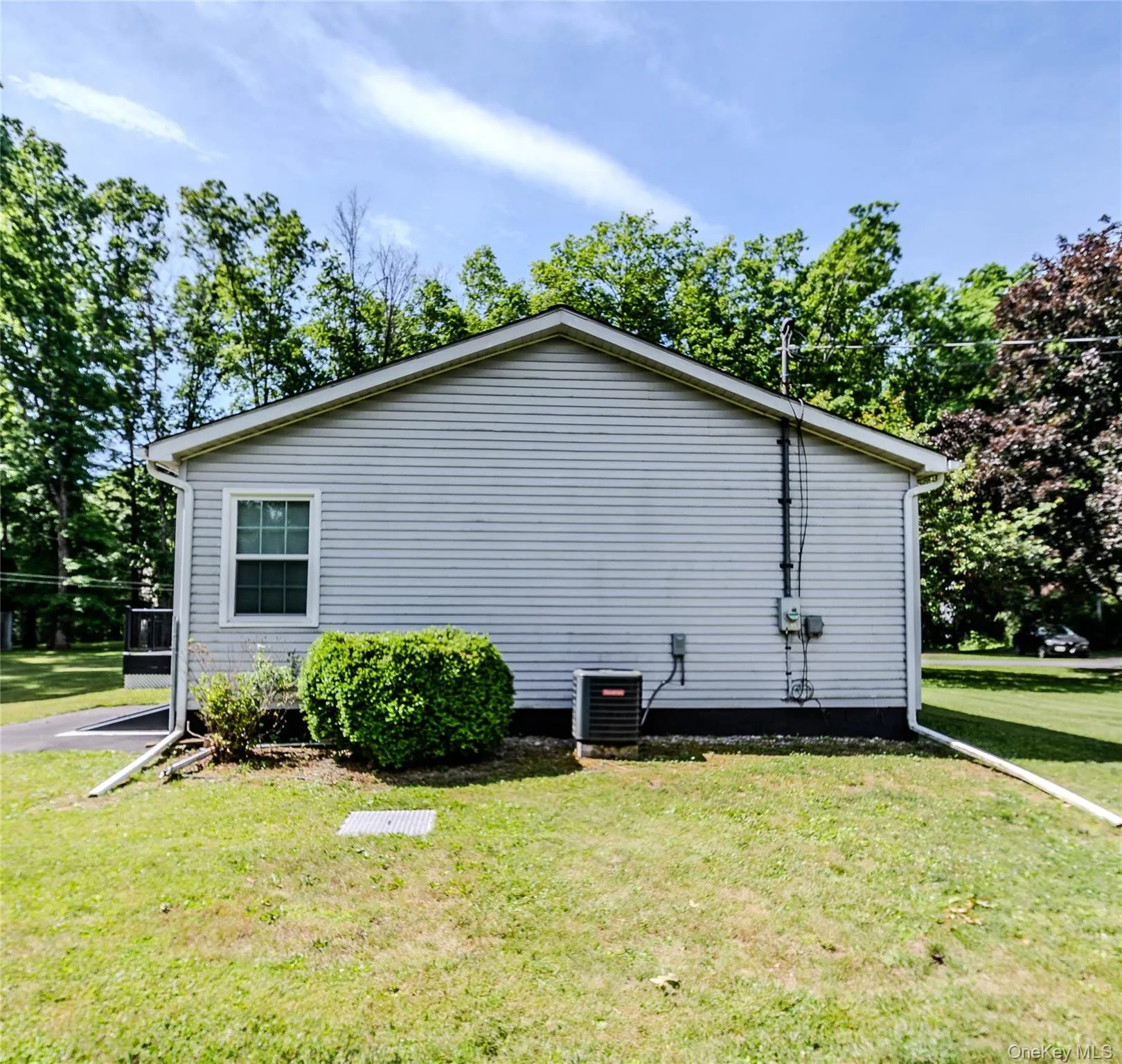 Light-toned siding exterior with a pitched roof, featuring a double-hung window with white trim, a visible HVAC unit, and a well-maintained lawn Light-toned siding exterior with a pitched roof, featuring a double-hung window with white trim, a visible HVAC unit, and a well-maintained lawn